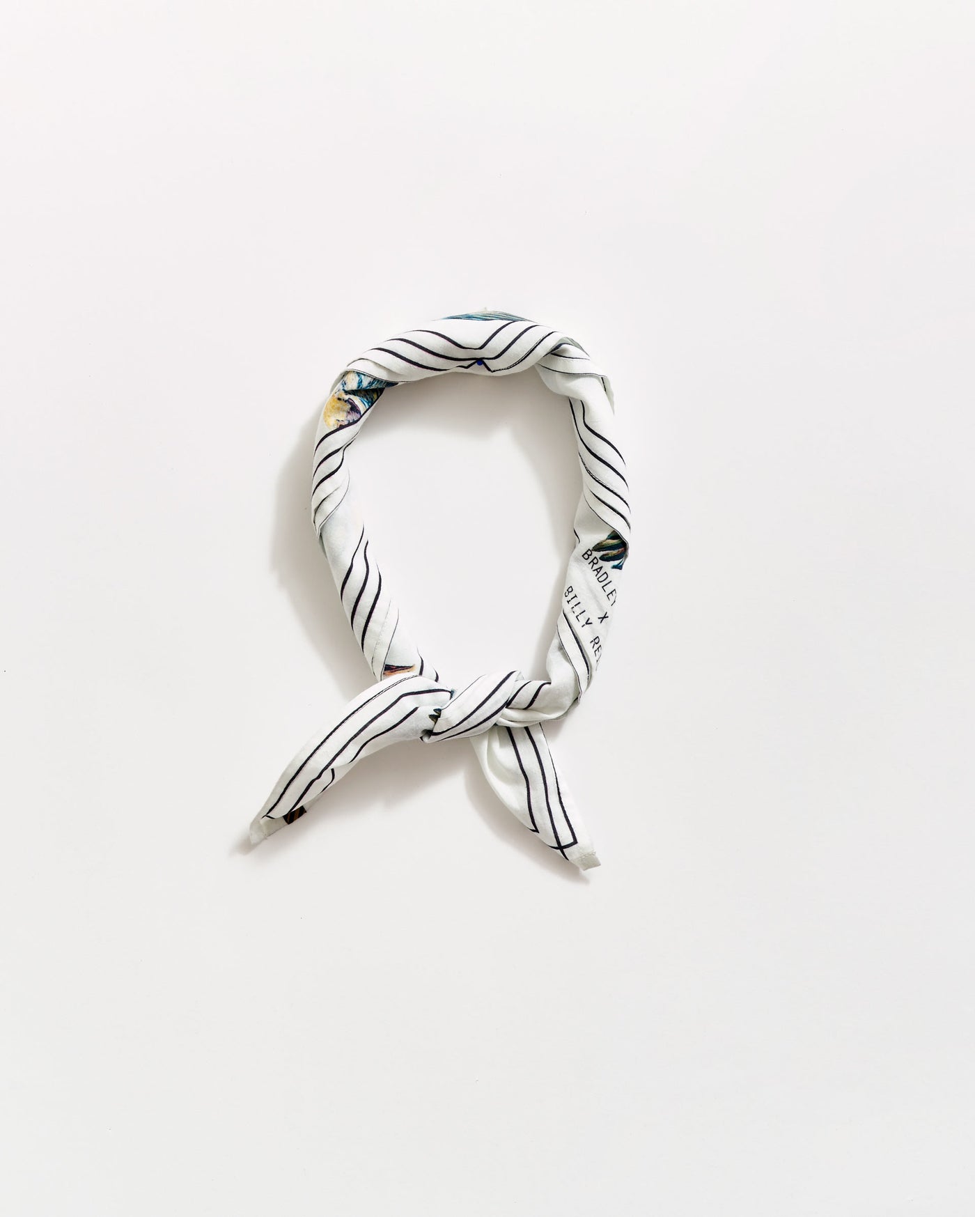 A white scarf with thin black diagonal stripes, tied in a loose knot and arranged in an oval shape on a plain white background.