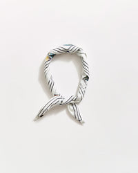 A white scarf with thin black diagonal stripes, tied in a loose knot and arranged in an oval shape on a plain white background.