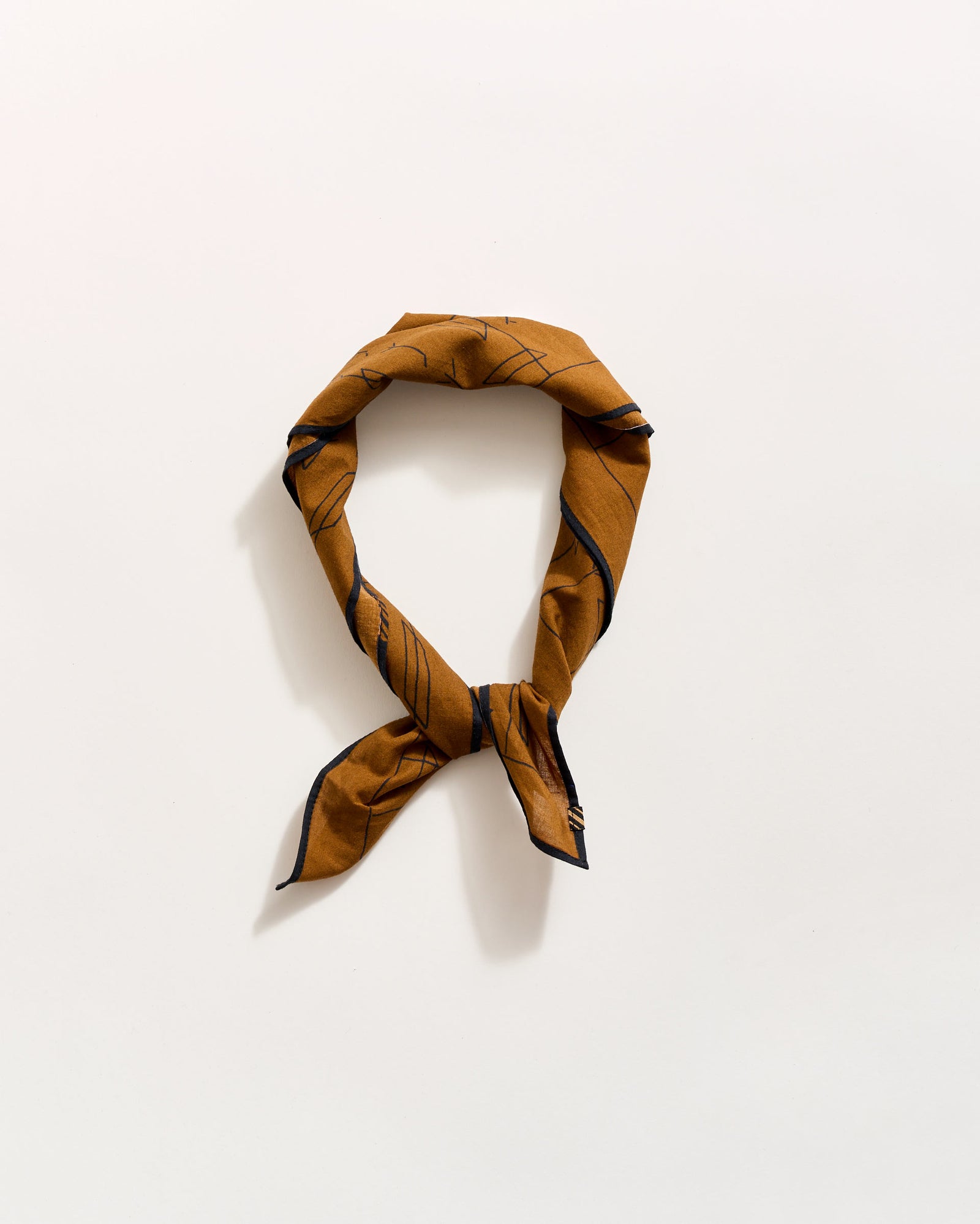 A brown patterned scarf is tied in a loose knot against a plain white background.
