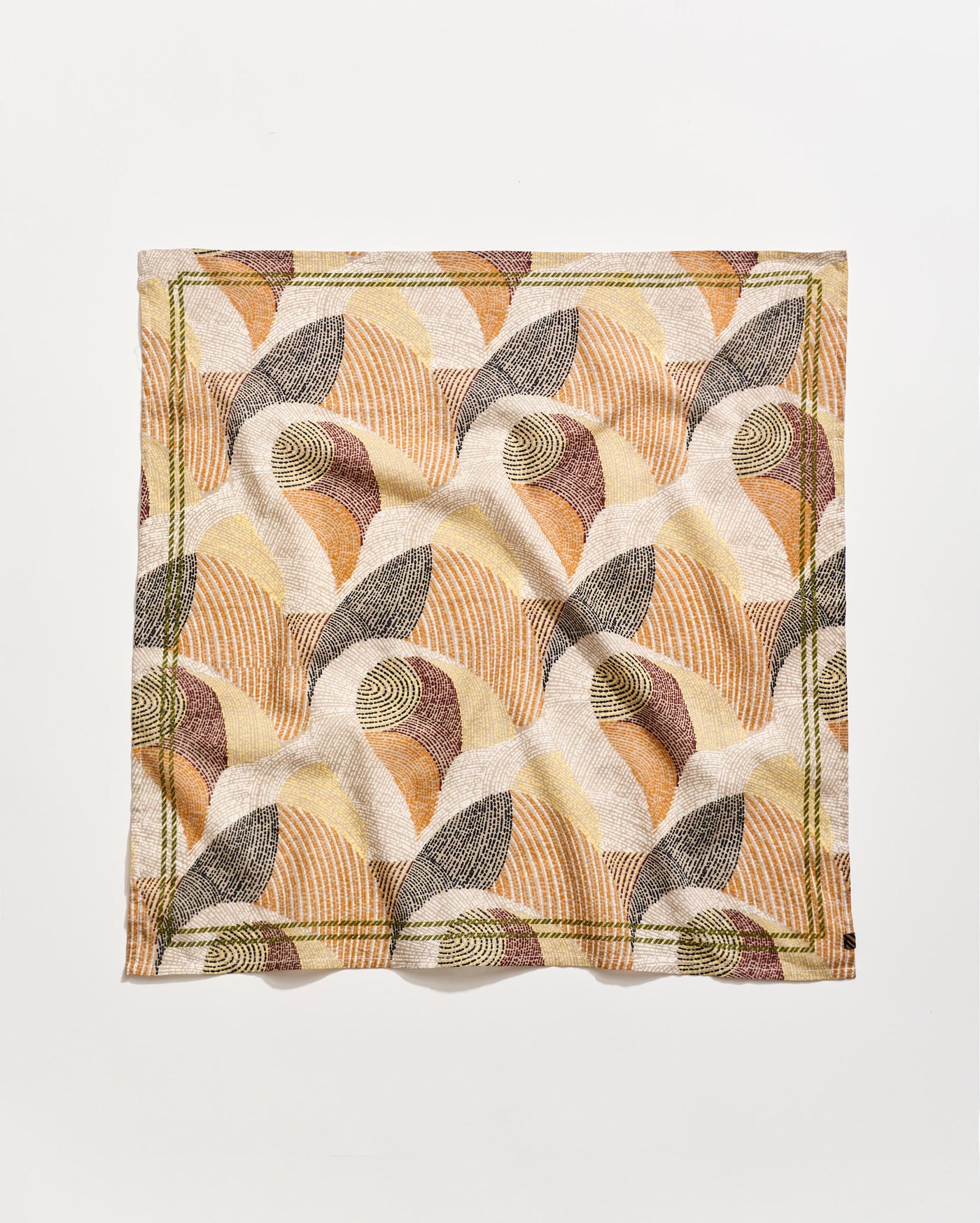 A square cloth napkin with an abstract, geometric pattern in earthy tones of beige, brown, rust, and olive green, featuring curved lines and shapes on a white background. The napkin is slightly wrinkled.