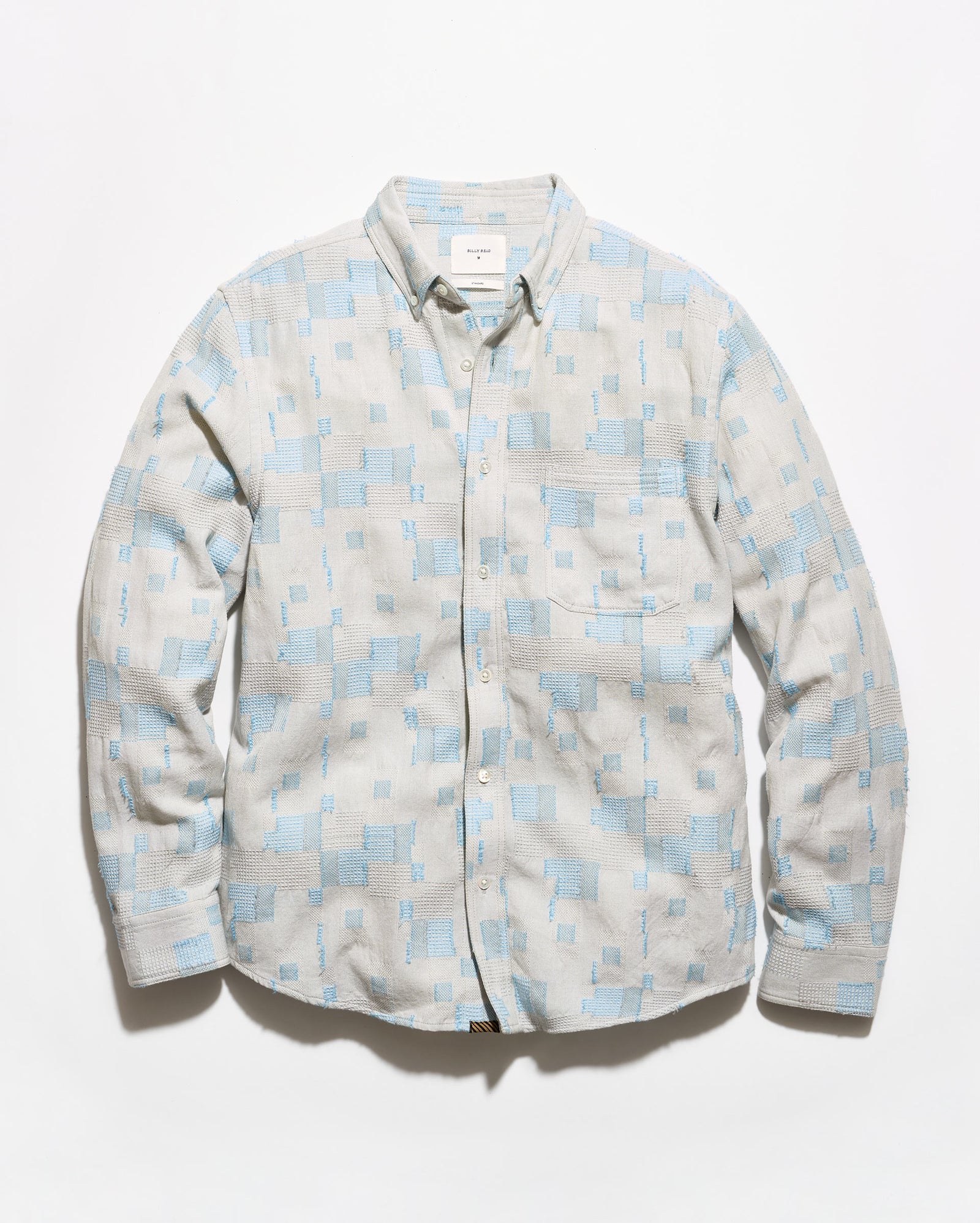 A long-sleeve button-up shirt with a light blue and off-white geometric pattern, laid flat against a white background.