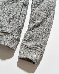 Close-up of a heather gray ribbed knit garment, showing the sleeve cuffs and textured fabric on a light gray background.