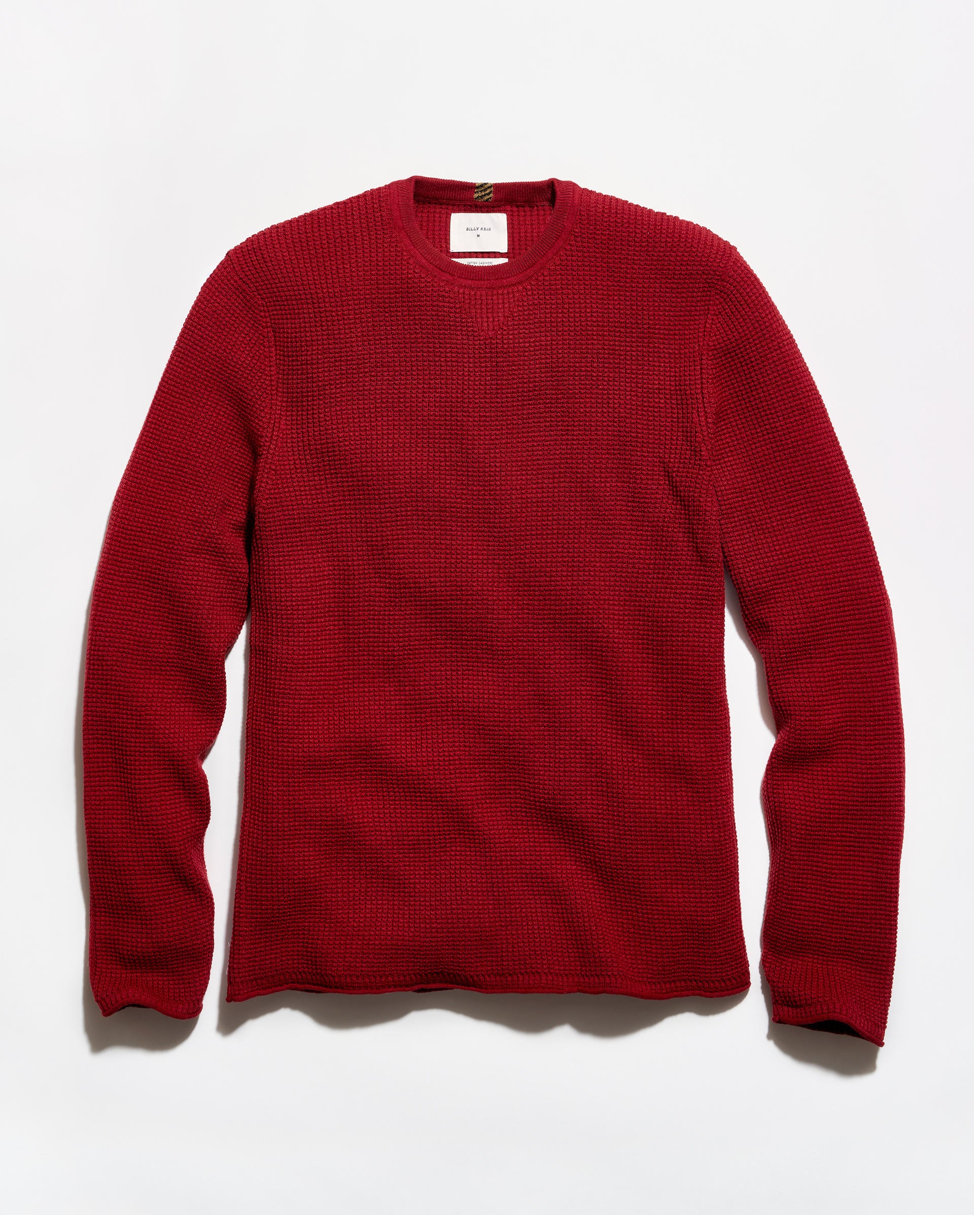 A red waffle-knit crewneck sweater laid flat against a white background.