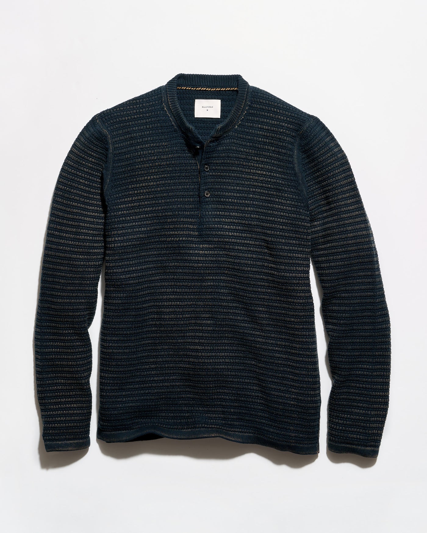 A dark navy blue long-sleeve henley shirt with a textured, fine horizontal stripe pattern, laid flat against a light gray background.