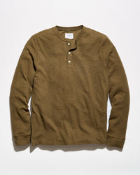 A brown long-sleeve henley shirt with a three-button placket, laid flat against a light gray background.