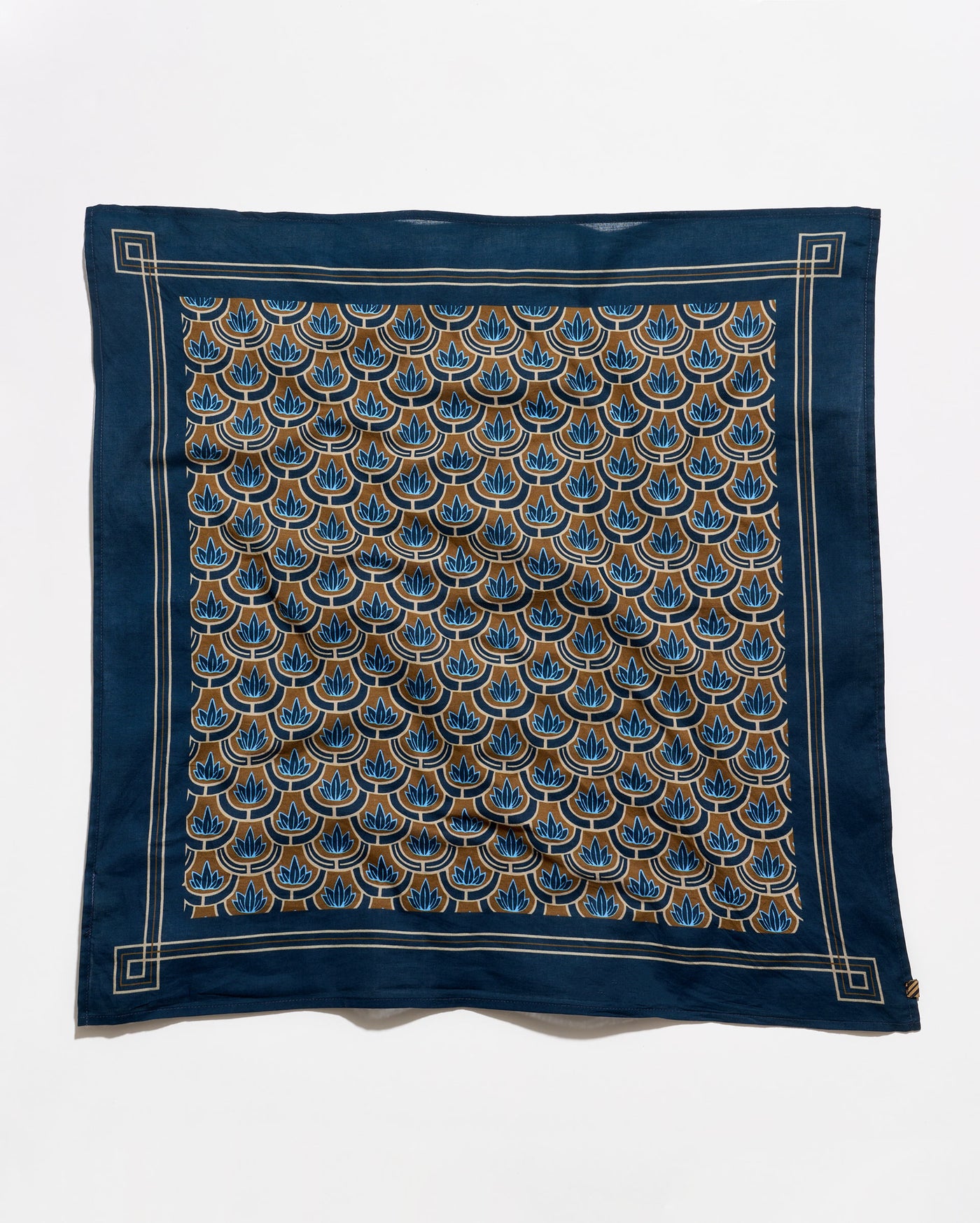 A square silk scarf featuring a navy blue border and a central pattern of repeating fan-shaped motifs in blue, gold, and beige, laid flat against a white background.