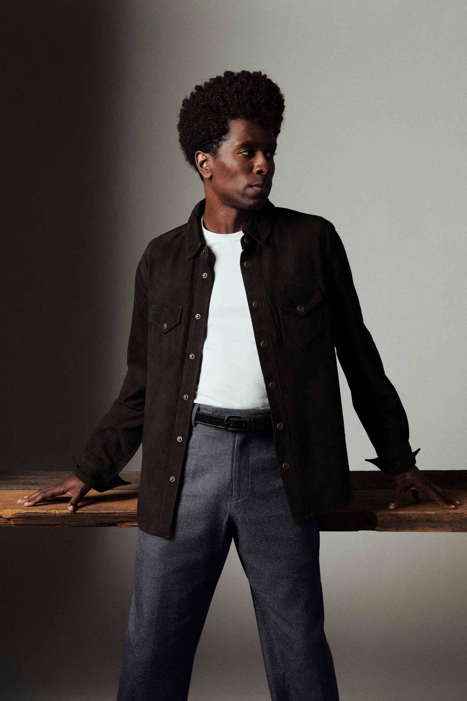 Man wearing a dark jacket and white shirt against a neutral background
