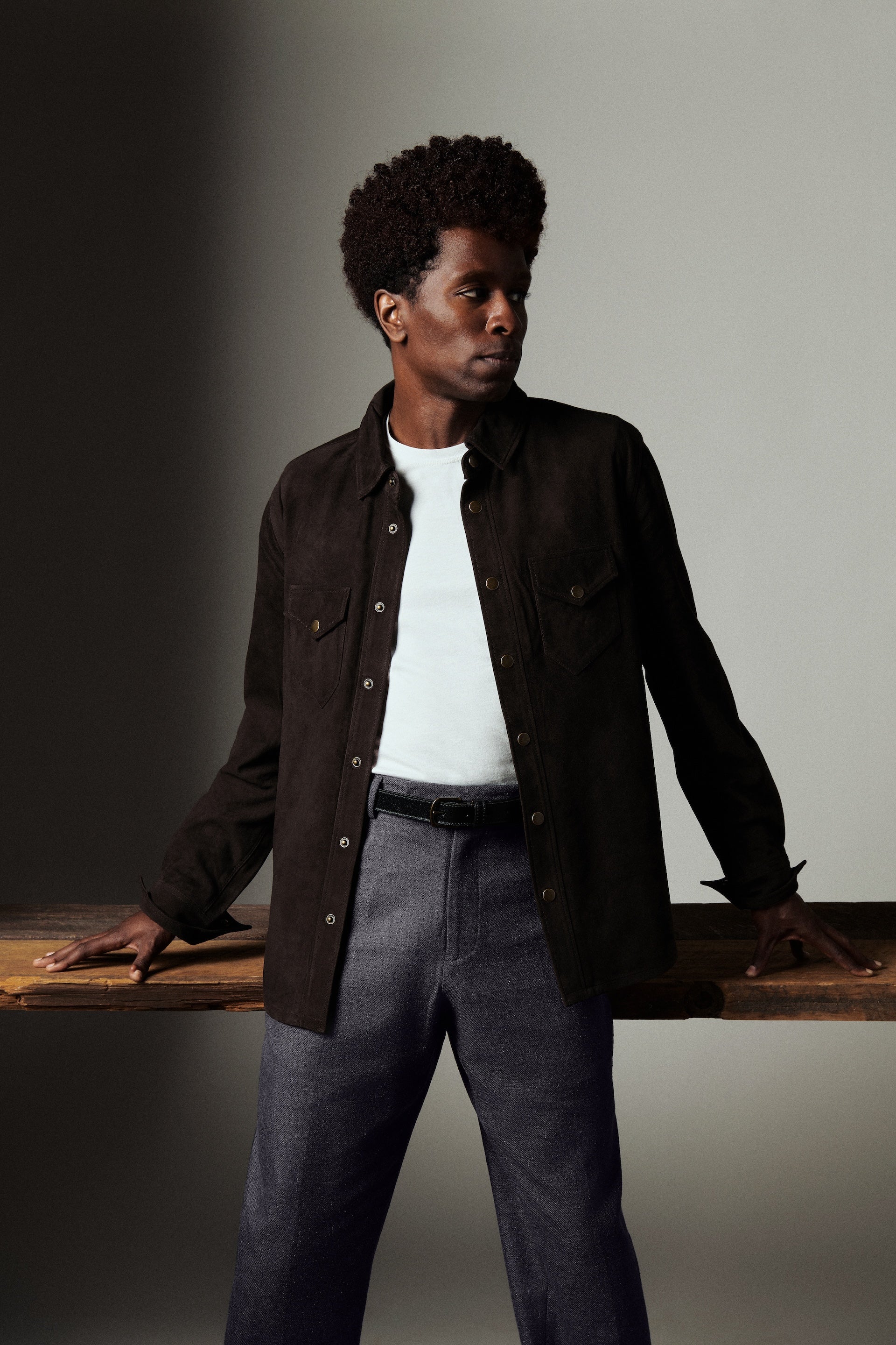 Man wearing a dark jacket and white shirt against a neutral background