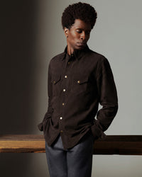 Person wearing a dark brown shirt with a neutral background