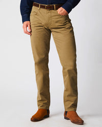 A person wearing tan khaki pants, a dark belt, a dark blue shirt, and brown suede boots, standing against a plain light background. The upper body and head are not visible.