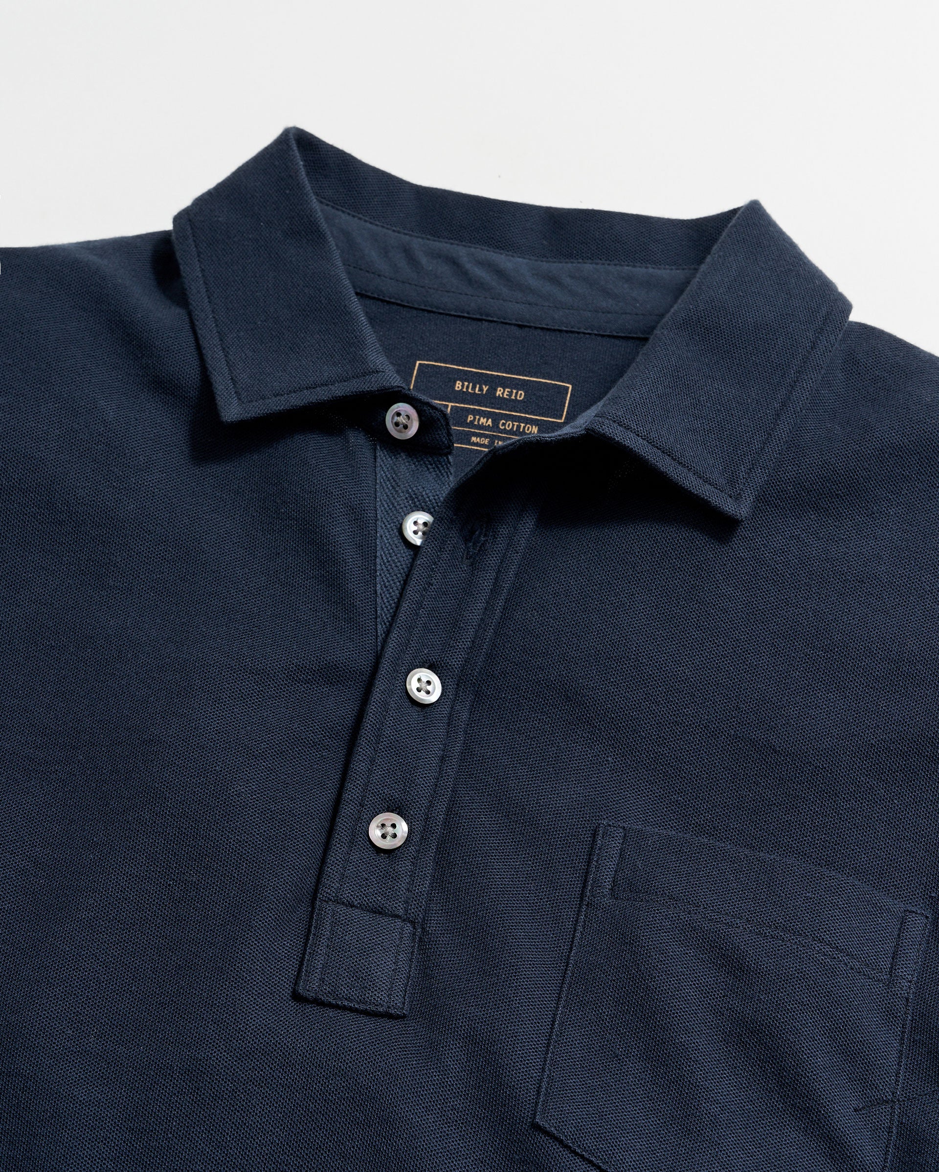 Navy polo shirt with brand label on a light gray background