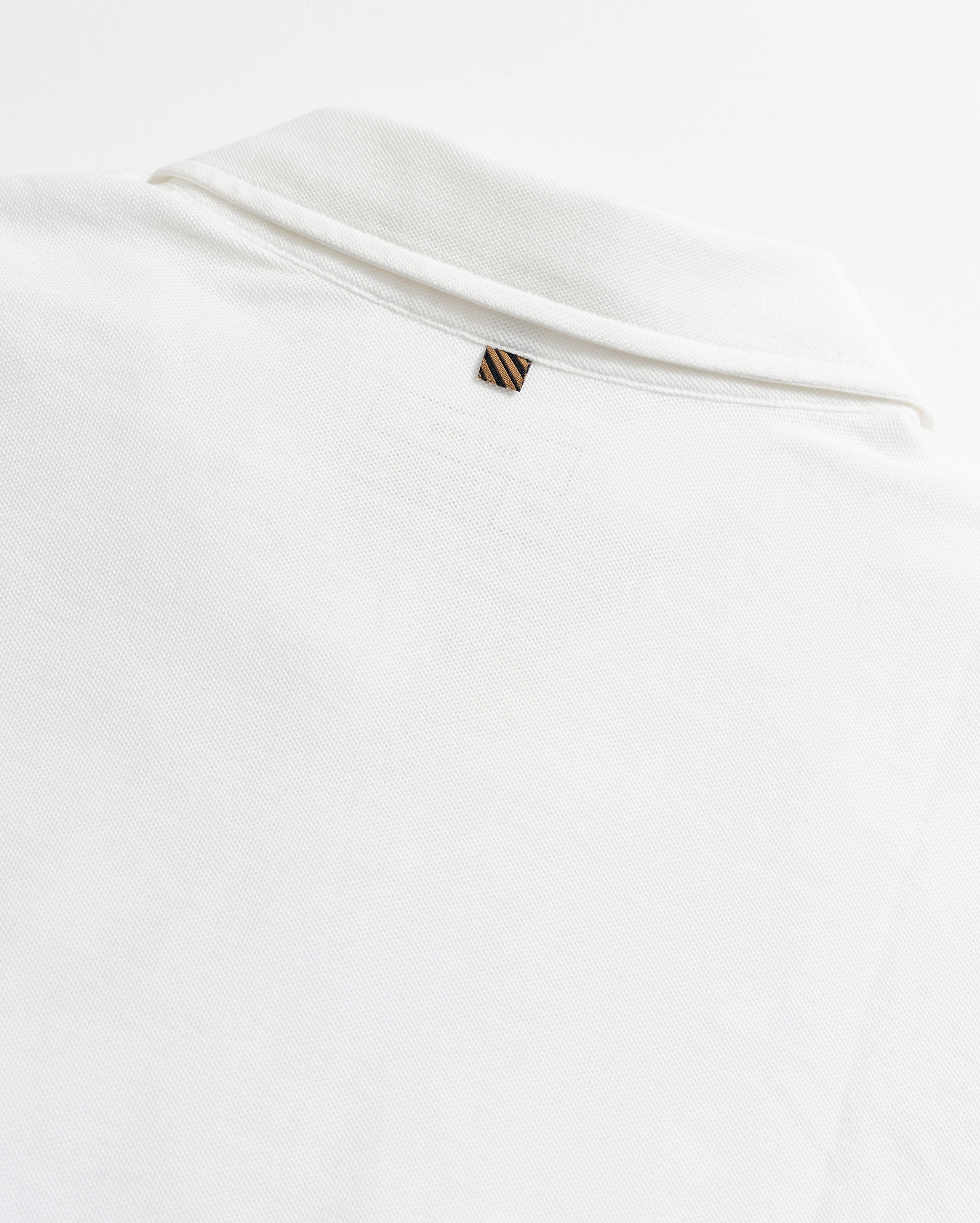 White shirt with a small logo on a light gray background