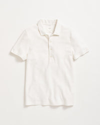 A plain white short-sleeve polo shirt with a collar and three buttons, laid flat on a white background.
