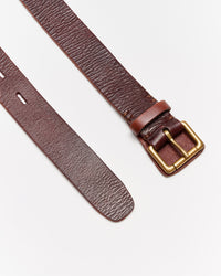 A brown leather belt with a gold rectangular buckle is laid flat on a white surface. One end shows punched holes, while the other end has the buckle attached.