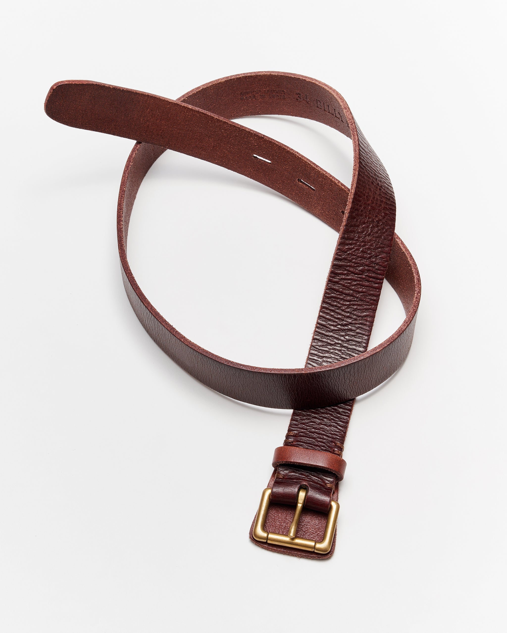 A brown leather belt with a gold buckle is laid out in a loose spiral on a white background.