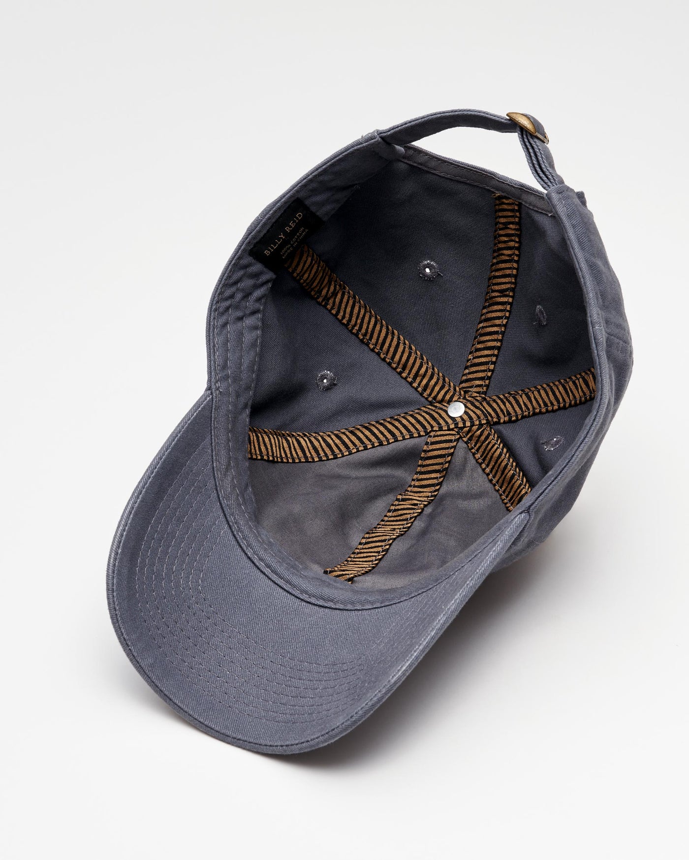 A gray baseball cap is shown upside down, revealing its interior stitching, adjustment strap, and metal eyelets against a white background.