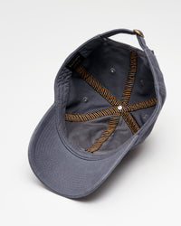 A gray baseball cap is shown upside down, revealing its interior stitching, adjustment strap, and metal eyelets against a white background.