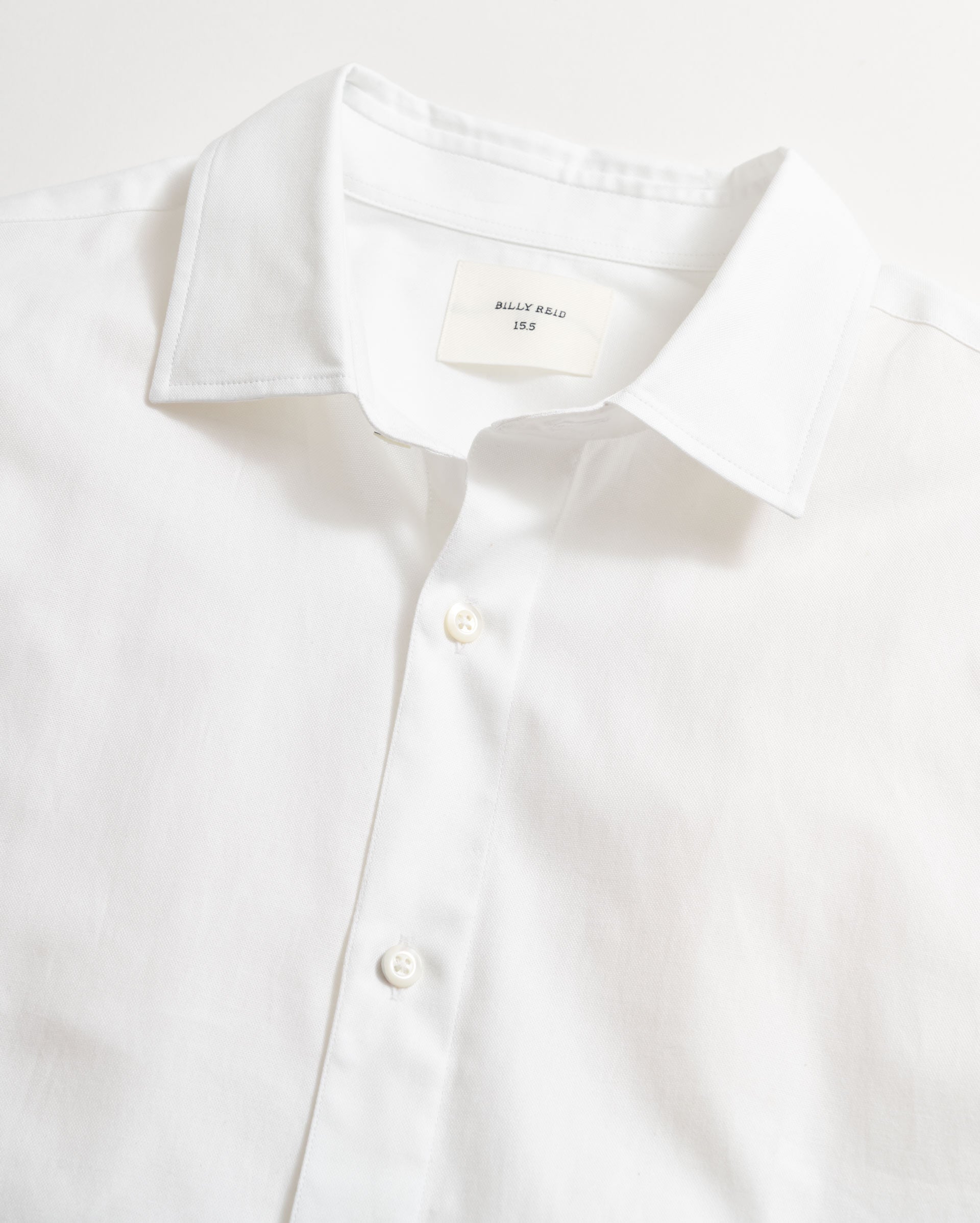 White dress shirt with collar and button details on a light gray background