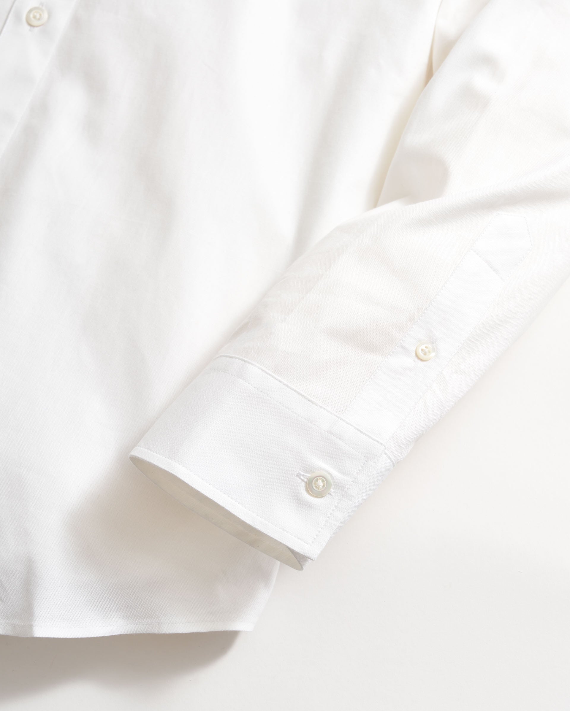 Close-up of a white shirt with rolled-up sleeve on a light background