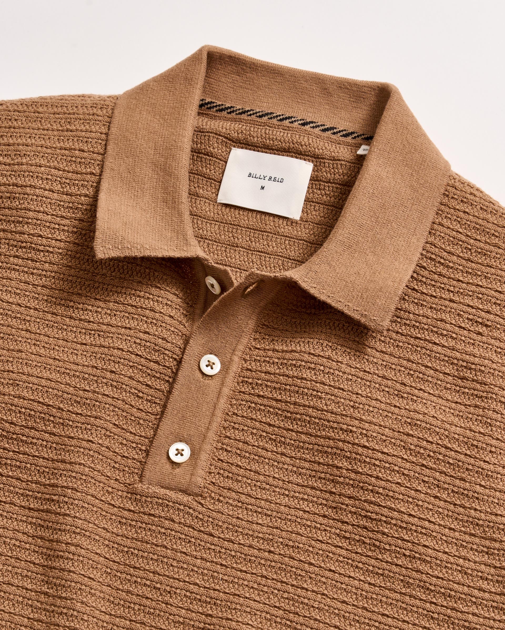 Brown ribbed knit polo shirt with a visible brand label on a light gray background