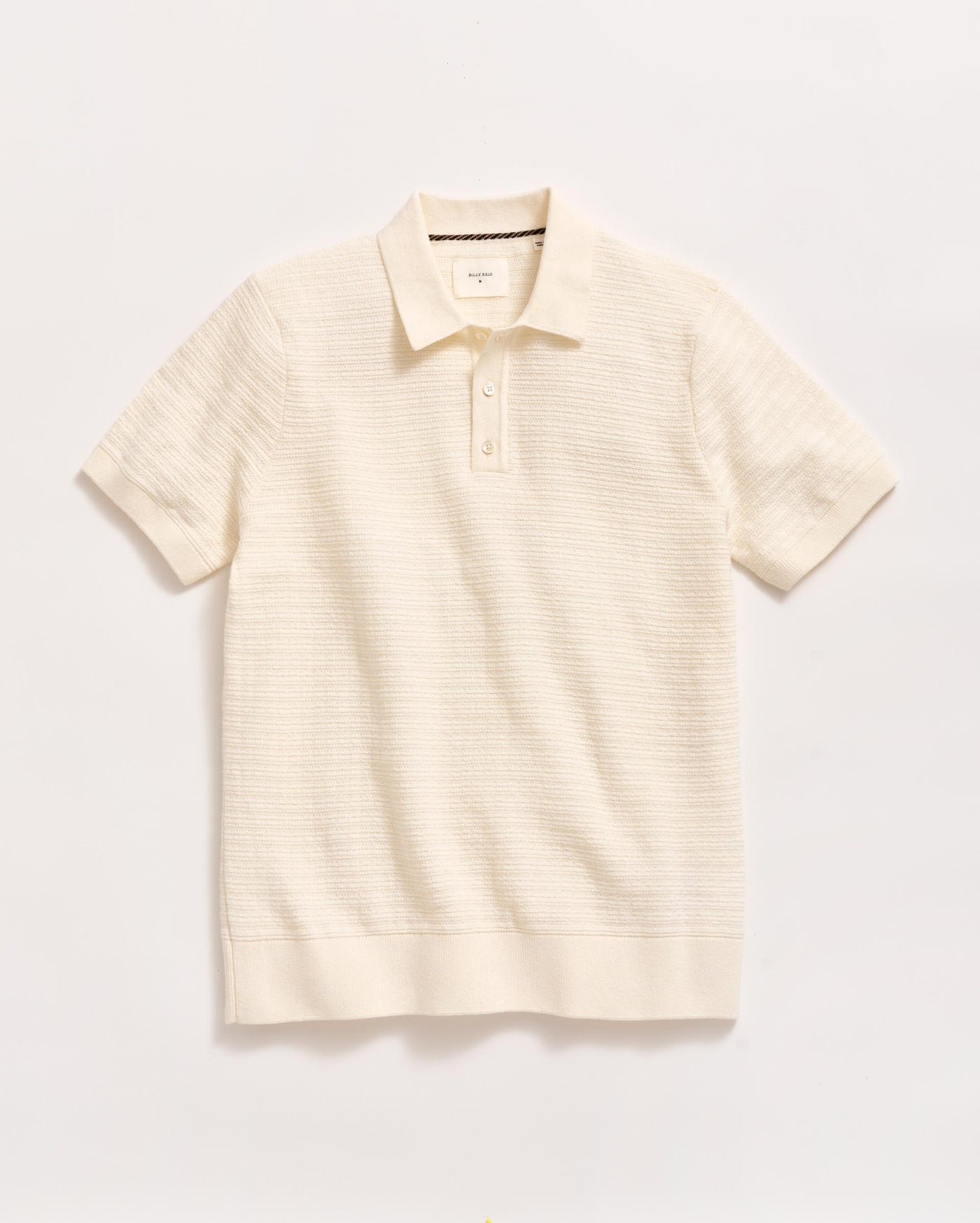 A short-sleeved, off-white knit polo shirt with a collar and a two-button placket, displayed flat against a plain white background.