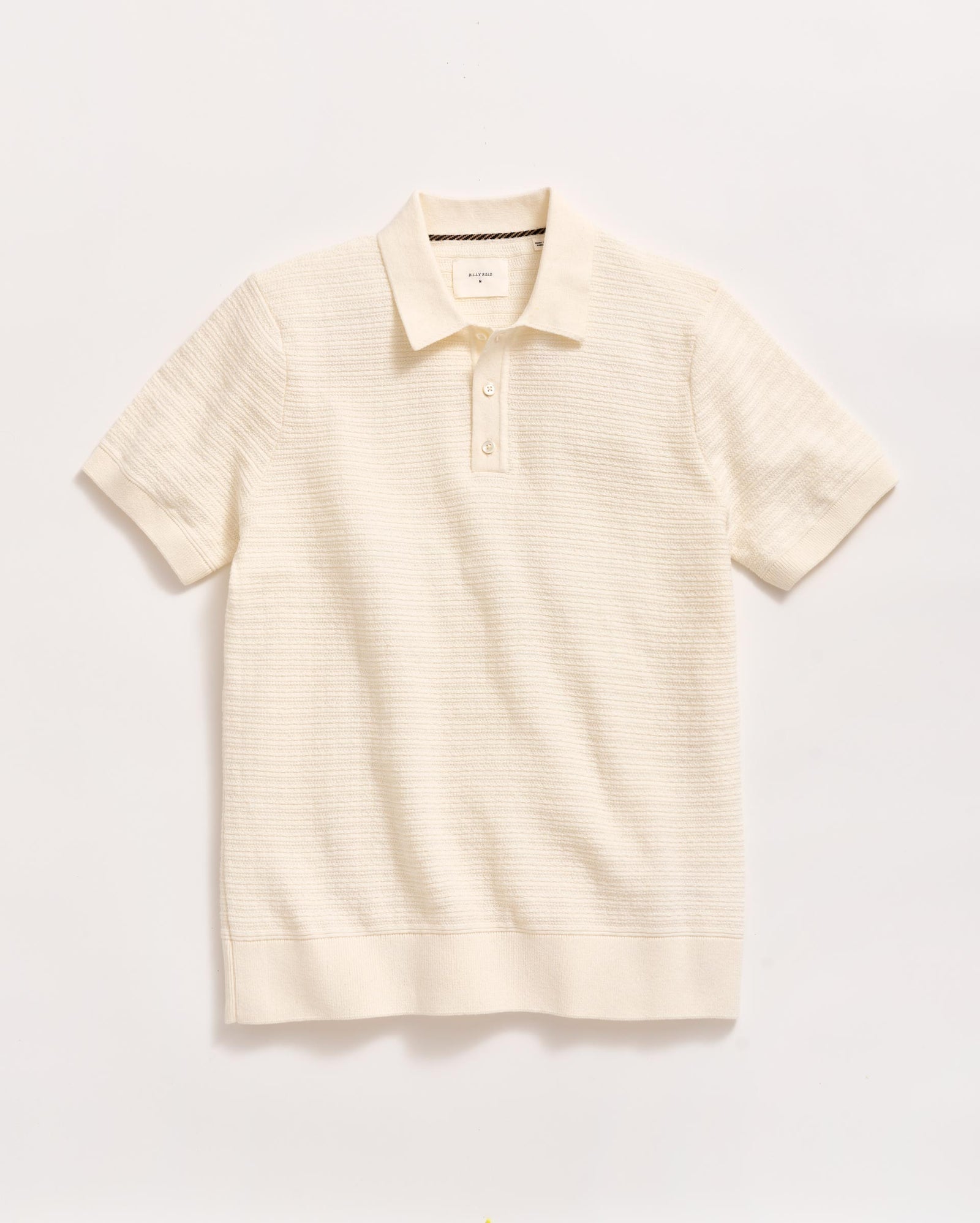 A short-sleeved, off-white knit polo shirt with a collar and a two-button placket, displayed flat against a plain white background.