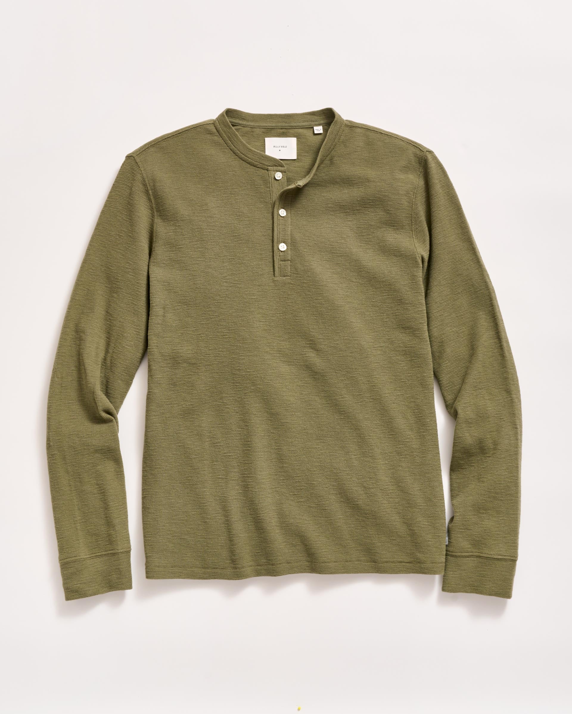 Olive green long-sleeve henley shirt with a round collar and three white buttons on the placket, laid flat on a light background.