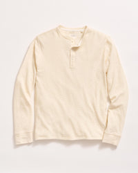 A long-sleeve, cream-colored henley shirt with a round neckline and three buttons down the front, laid flat on a white background.