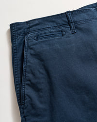 Close-up view of a pair of dark blue pants, showing the waistband, belt loop, and a welt pocket on a light background.