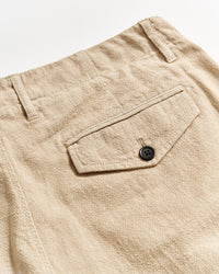 Close-up of beige textured pants showing a back pocket with a flap and a black button, along with belt loops and visible stitching details.