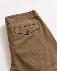 A close-up of a pair of folded brown textured pants, showing a back pocket with a black button and a belt loop on a light background.