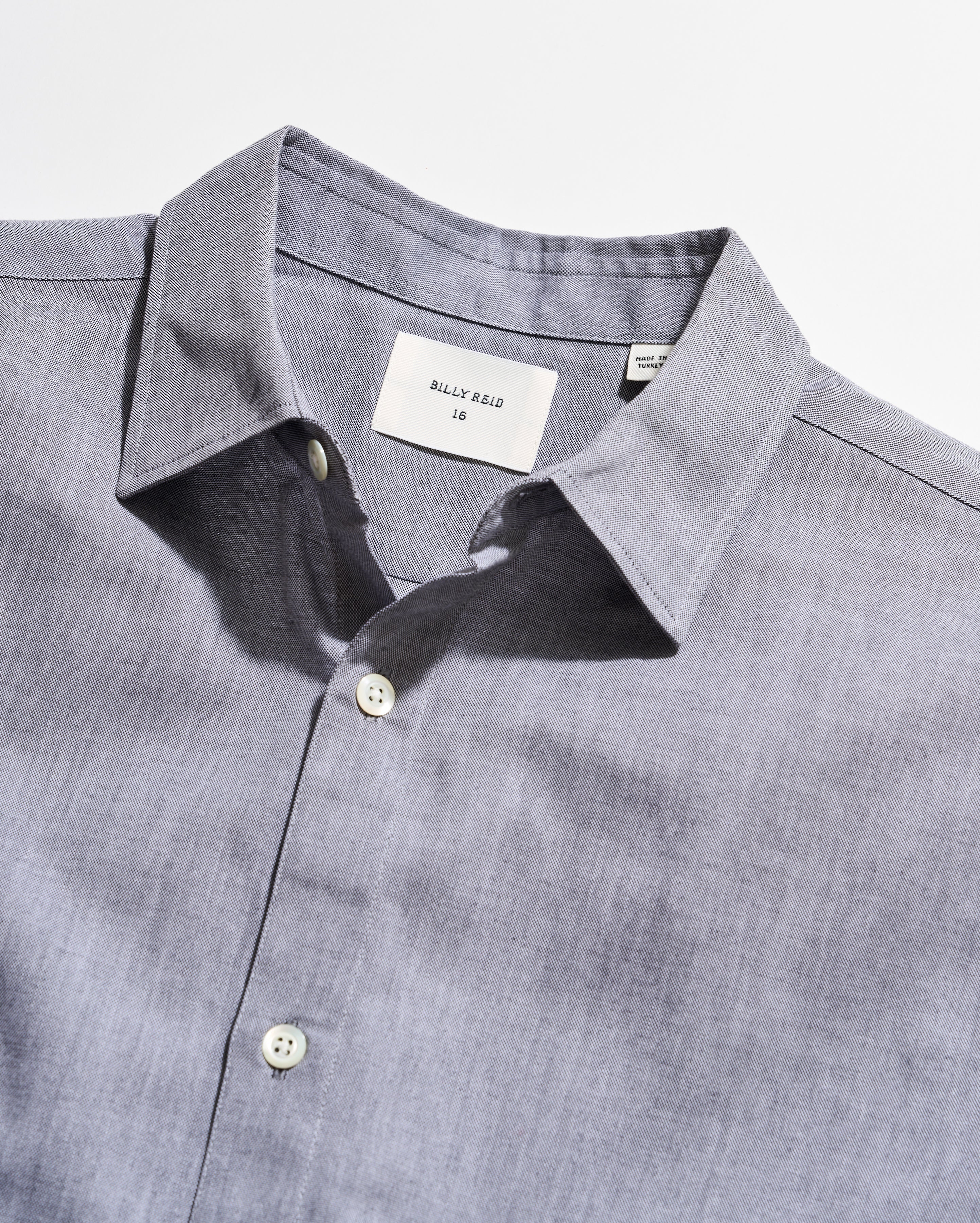 Close-up of a gray shirt with collar and buttons on a white background