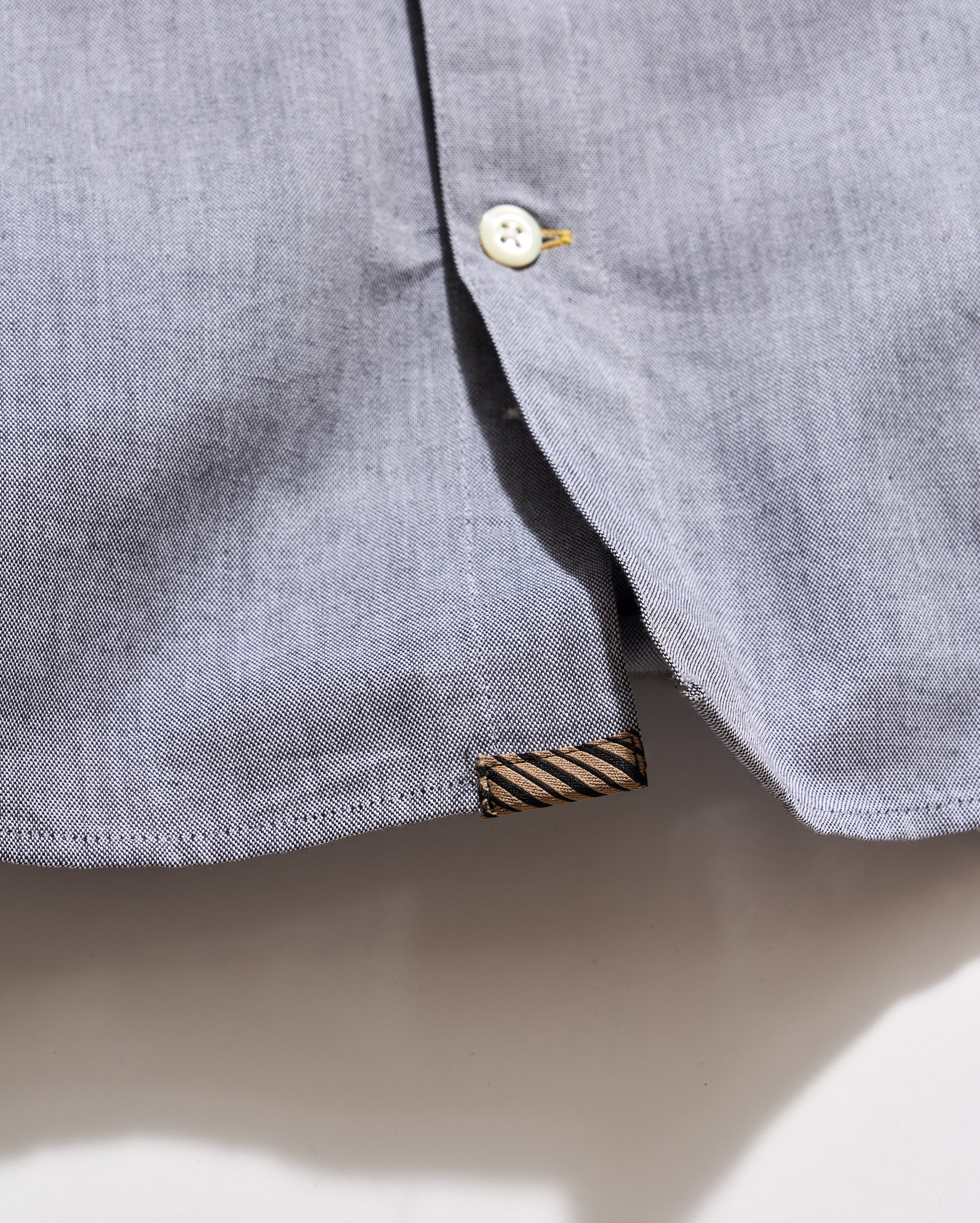 Close-up of a gray shirt collar with a button and label on a light background