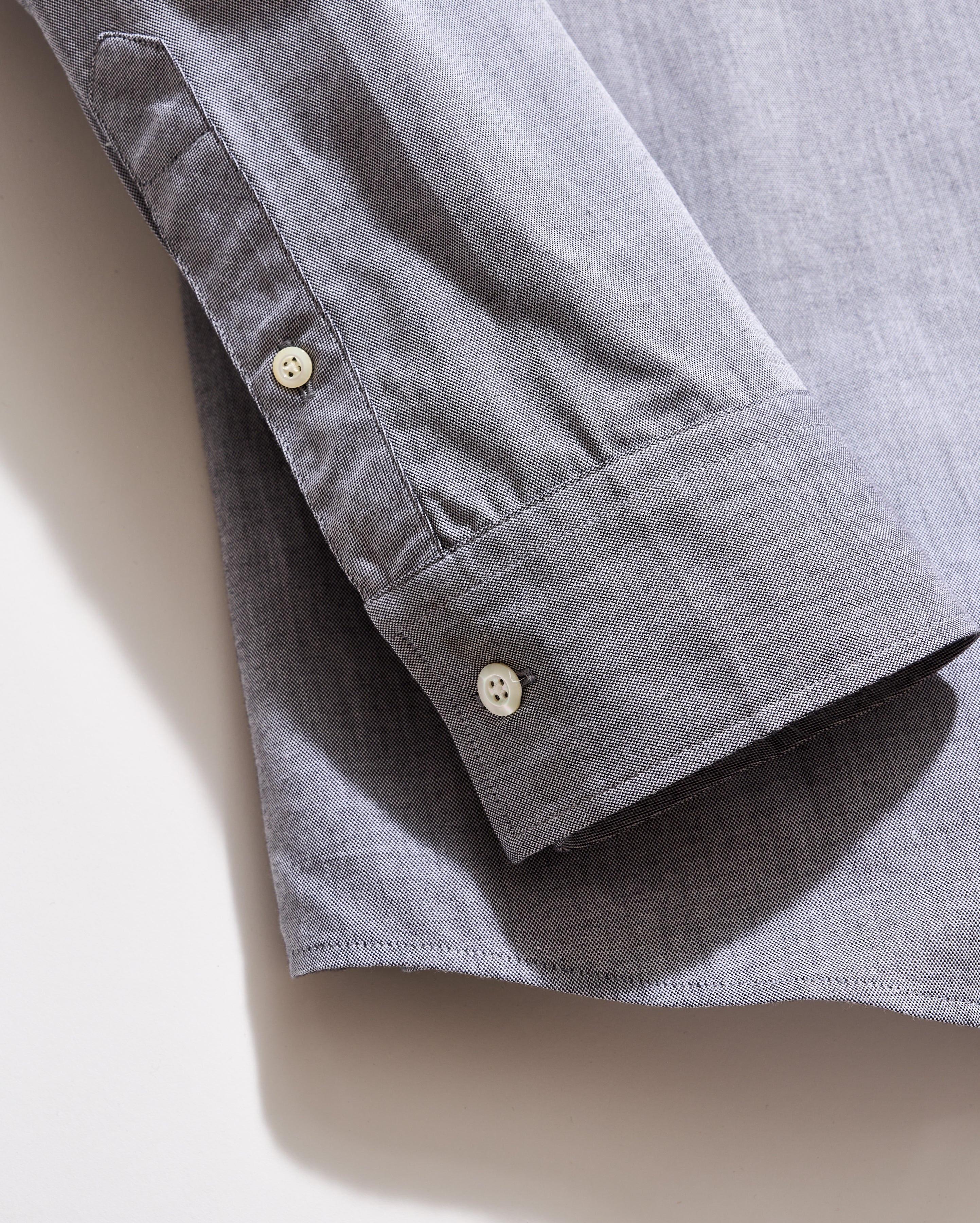 Close-up of a gray shirt with button details on a beige background