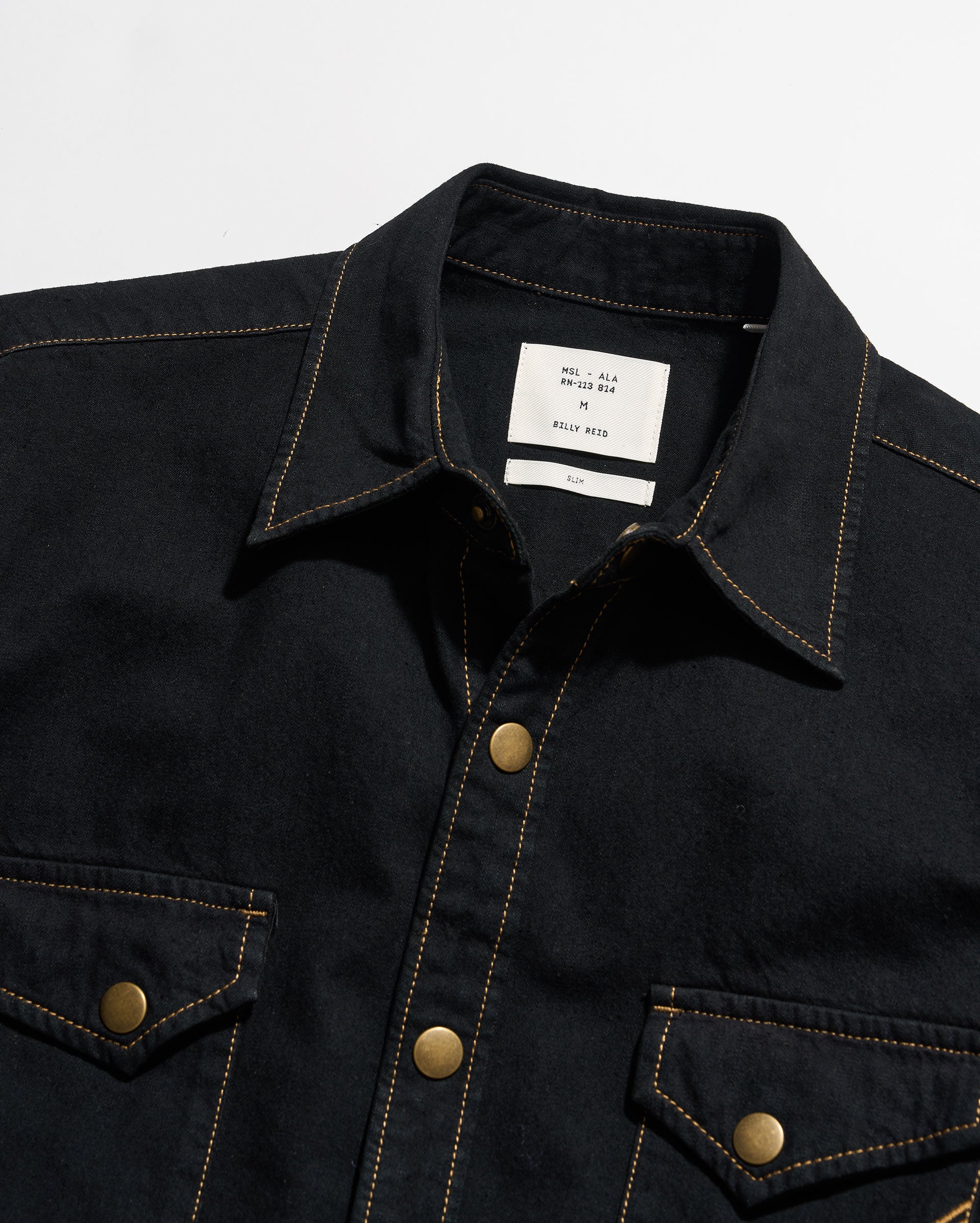 Black denim jacket with gold buttons on a white background