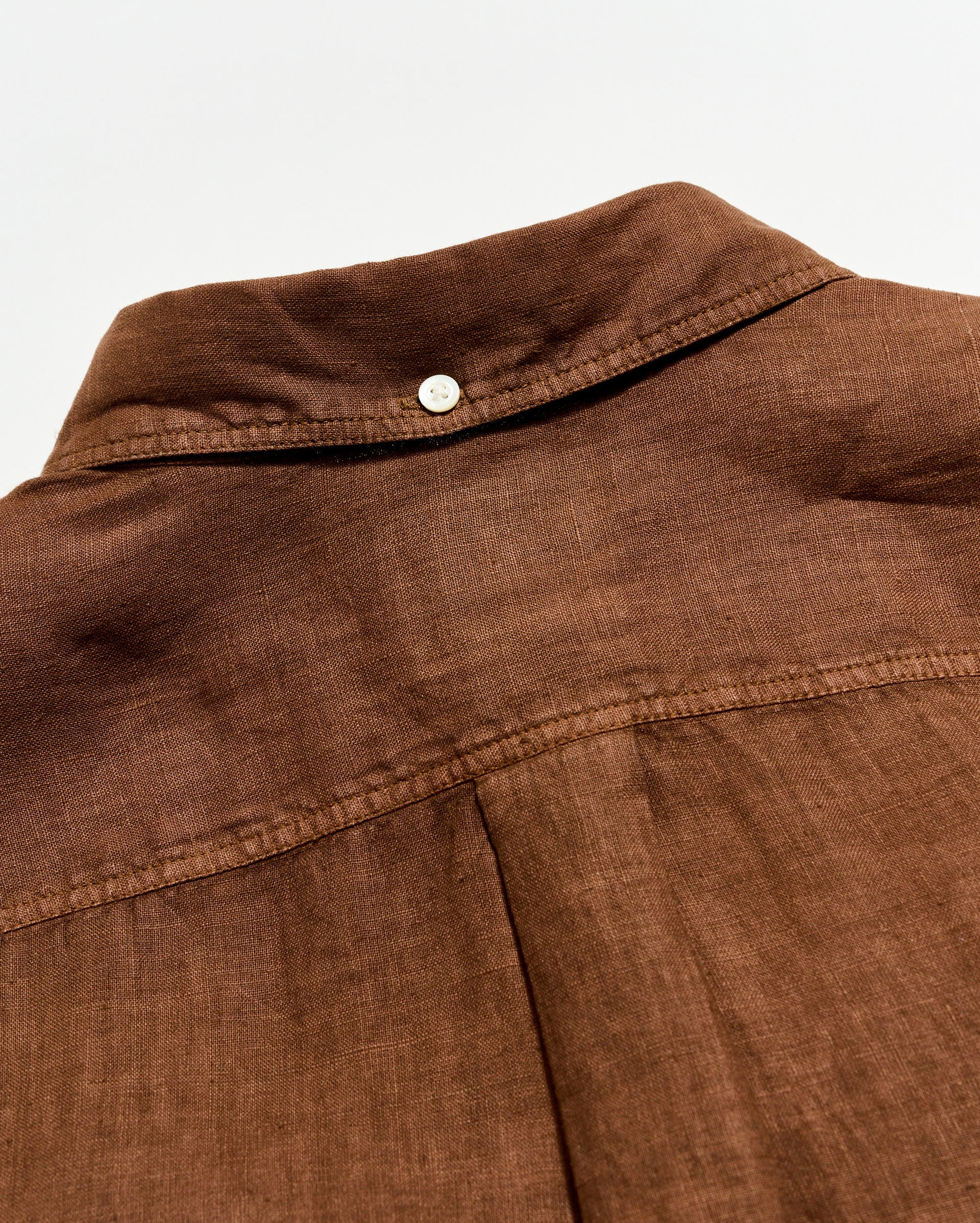 Close-up of a brown fabric garment with a button on a white background
