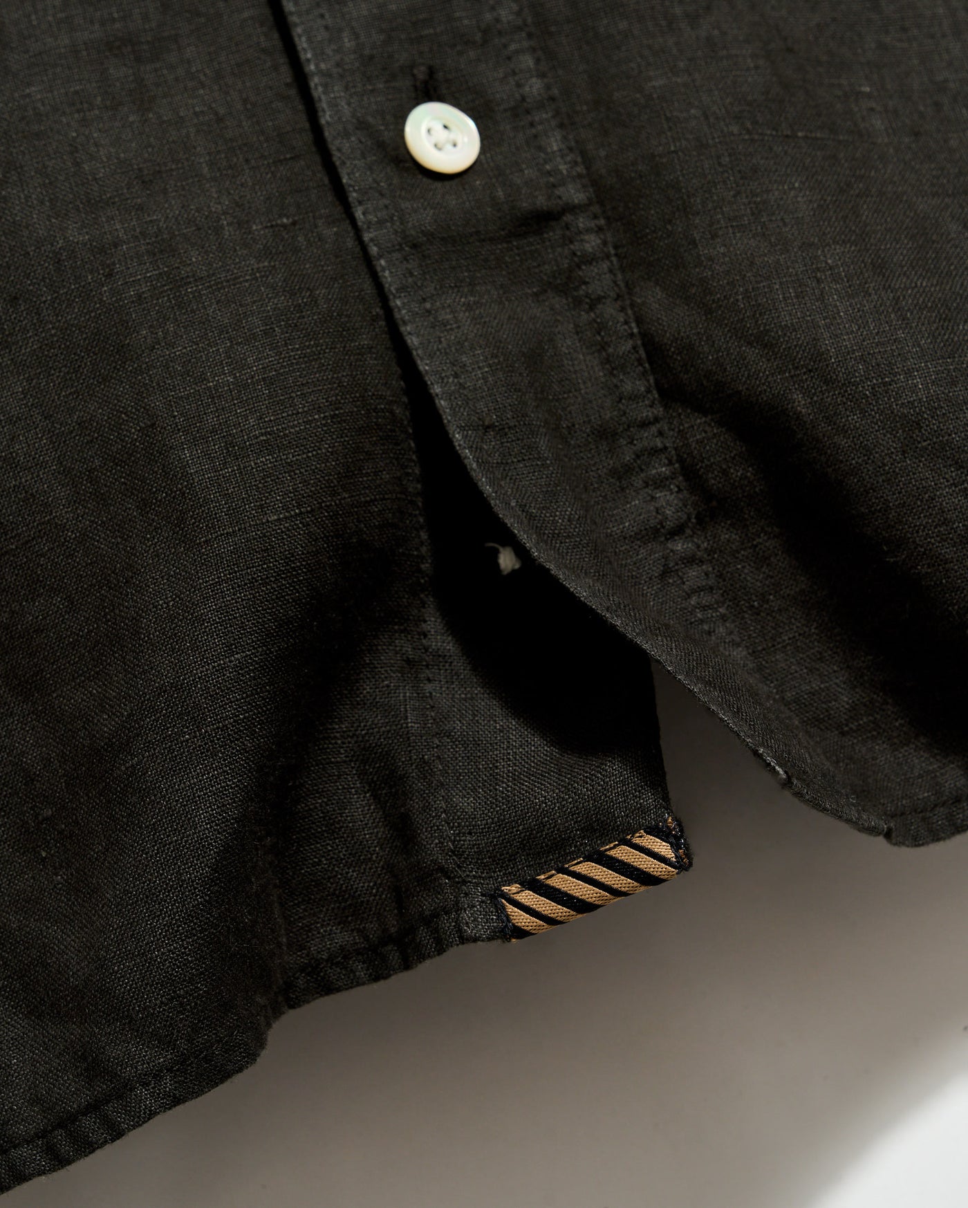 Close-up of a black shirt with a button on a neutral background
