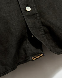 Close-up of a black shirt with a button on a neutral background