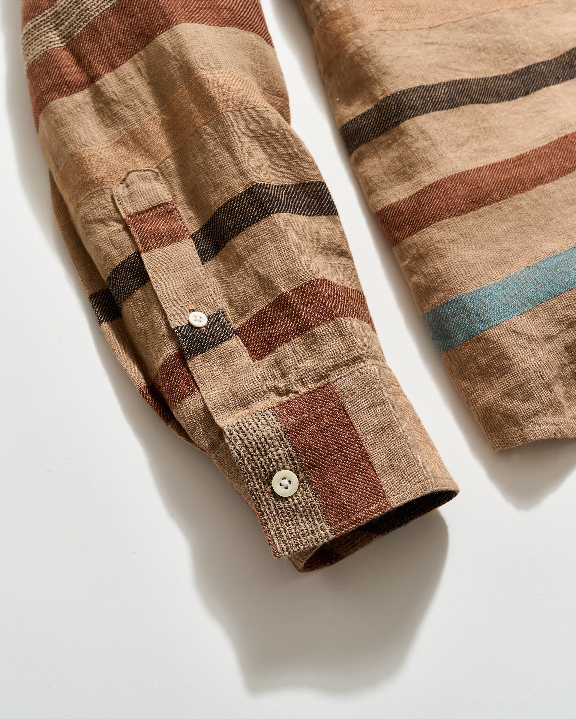 Close-up of a plaid shirt with brown, beige, and blue colors on a white background