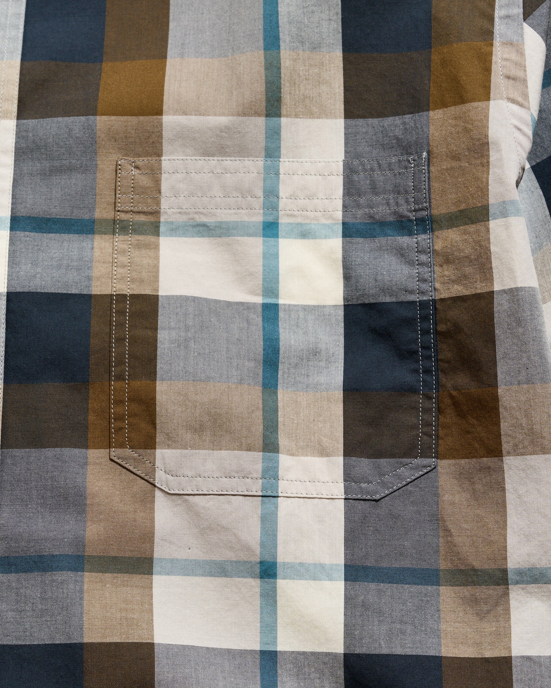 Close-up of a plaid shirt with brown, blue, and beige colors.