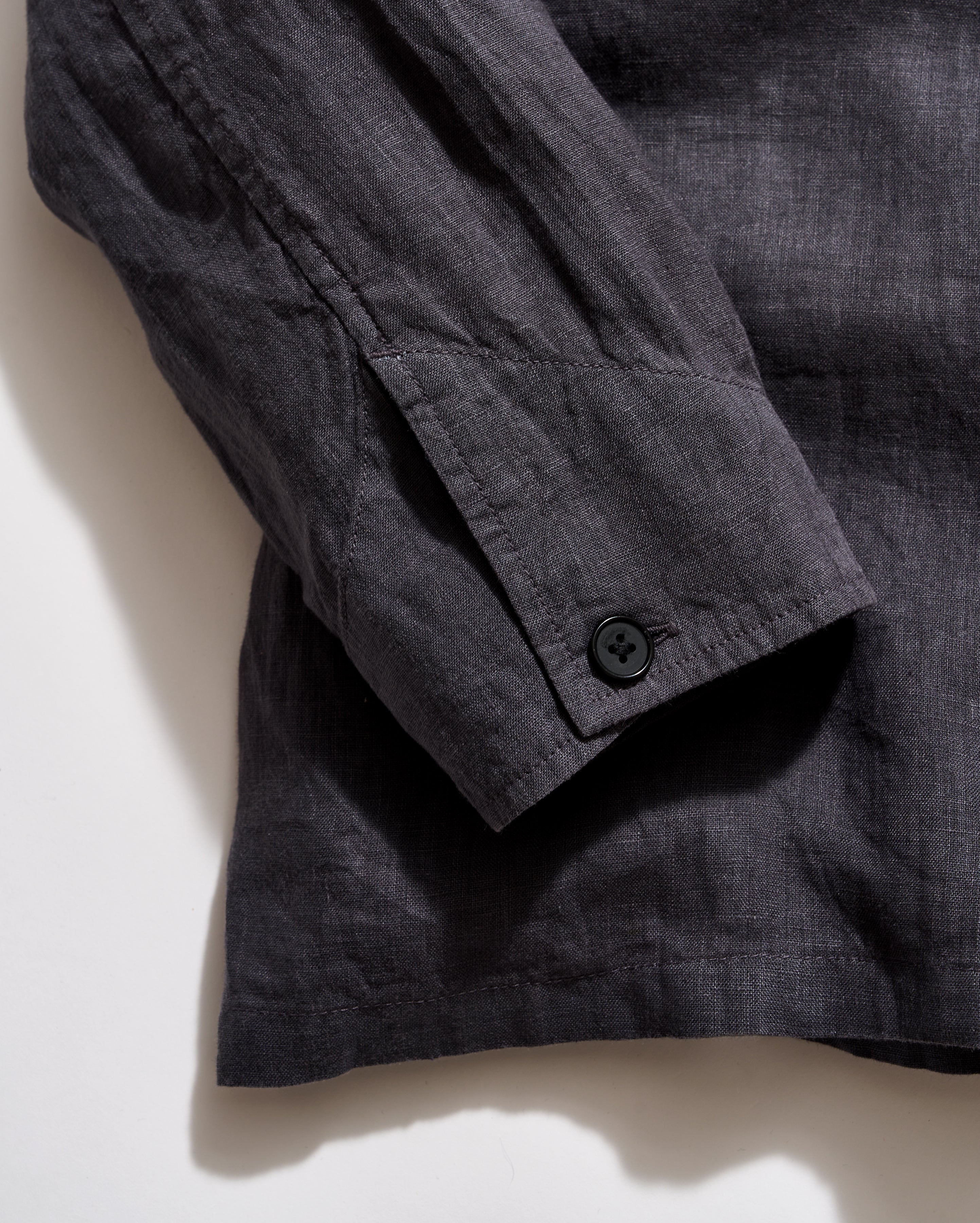 Dark gray shirt with button on a light beige background