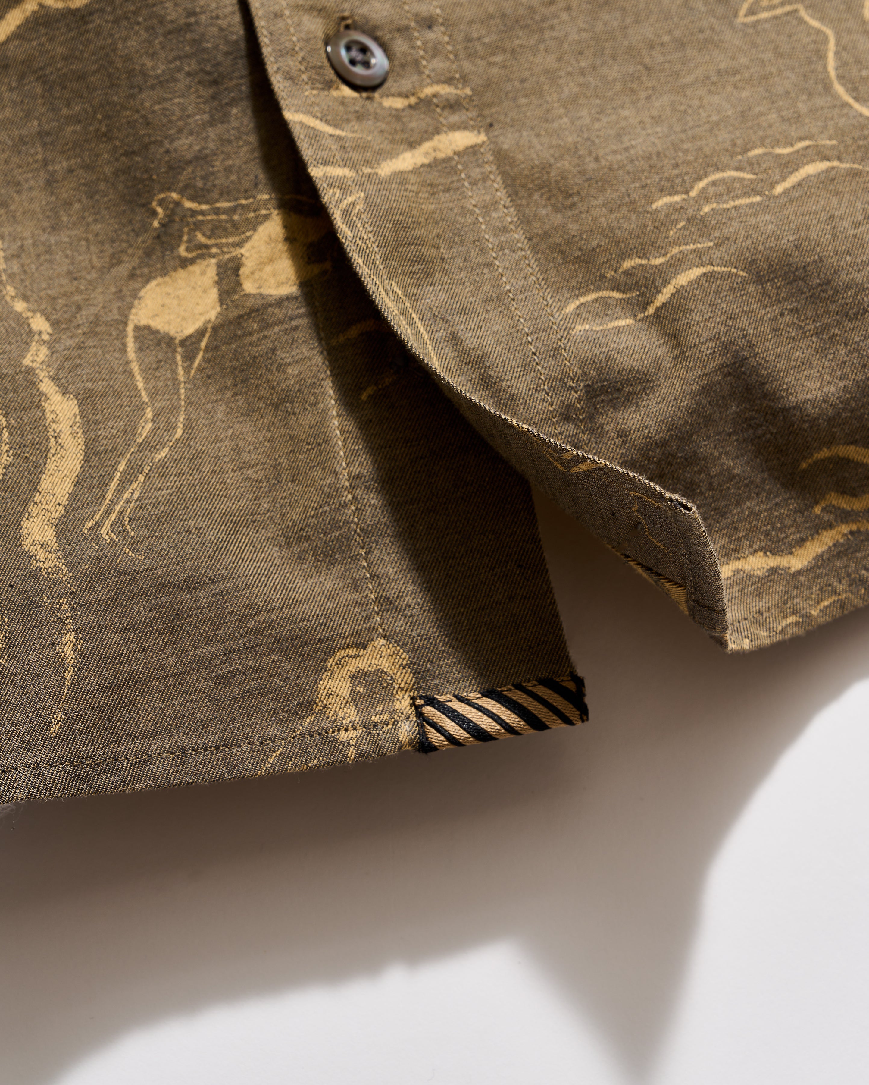 Close-up of a brown fabric with gold deer pattern on a white background