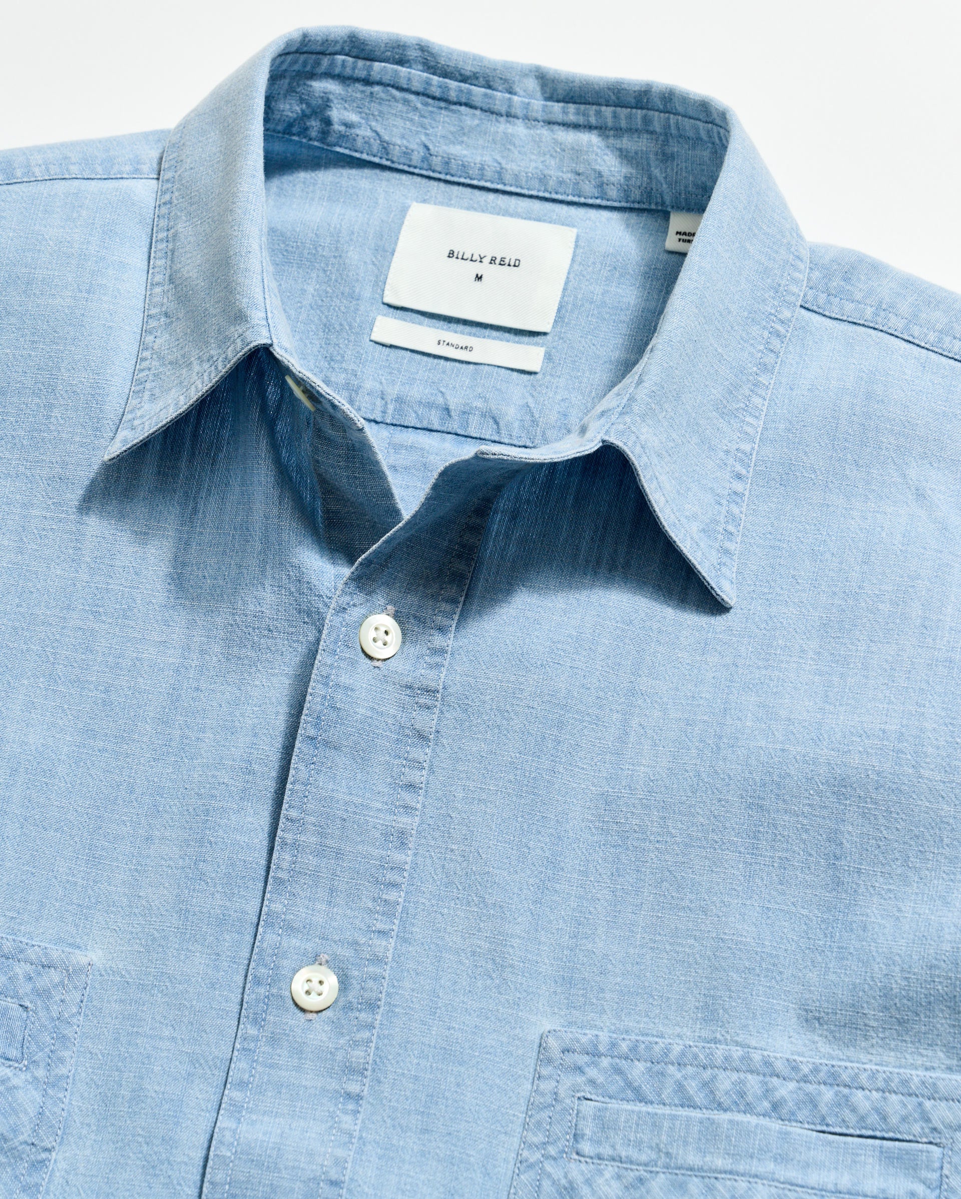 Light blue shirt with collar and button details on a light gray background