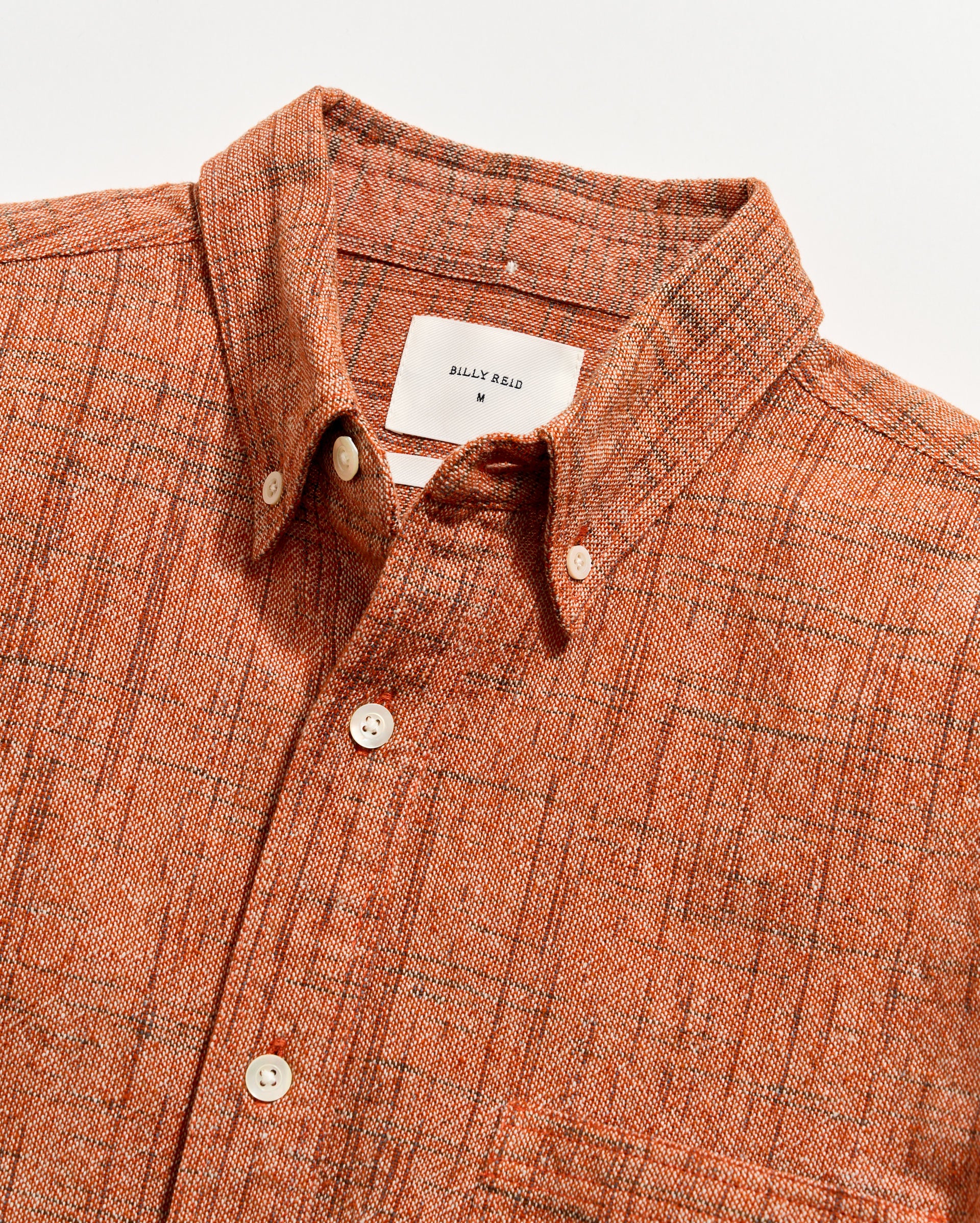 Orange checkered shirt with a label on a white background
