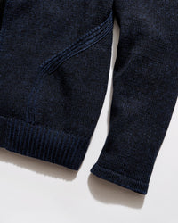 Close-up of a navy blue sweater on a light beige background