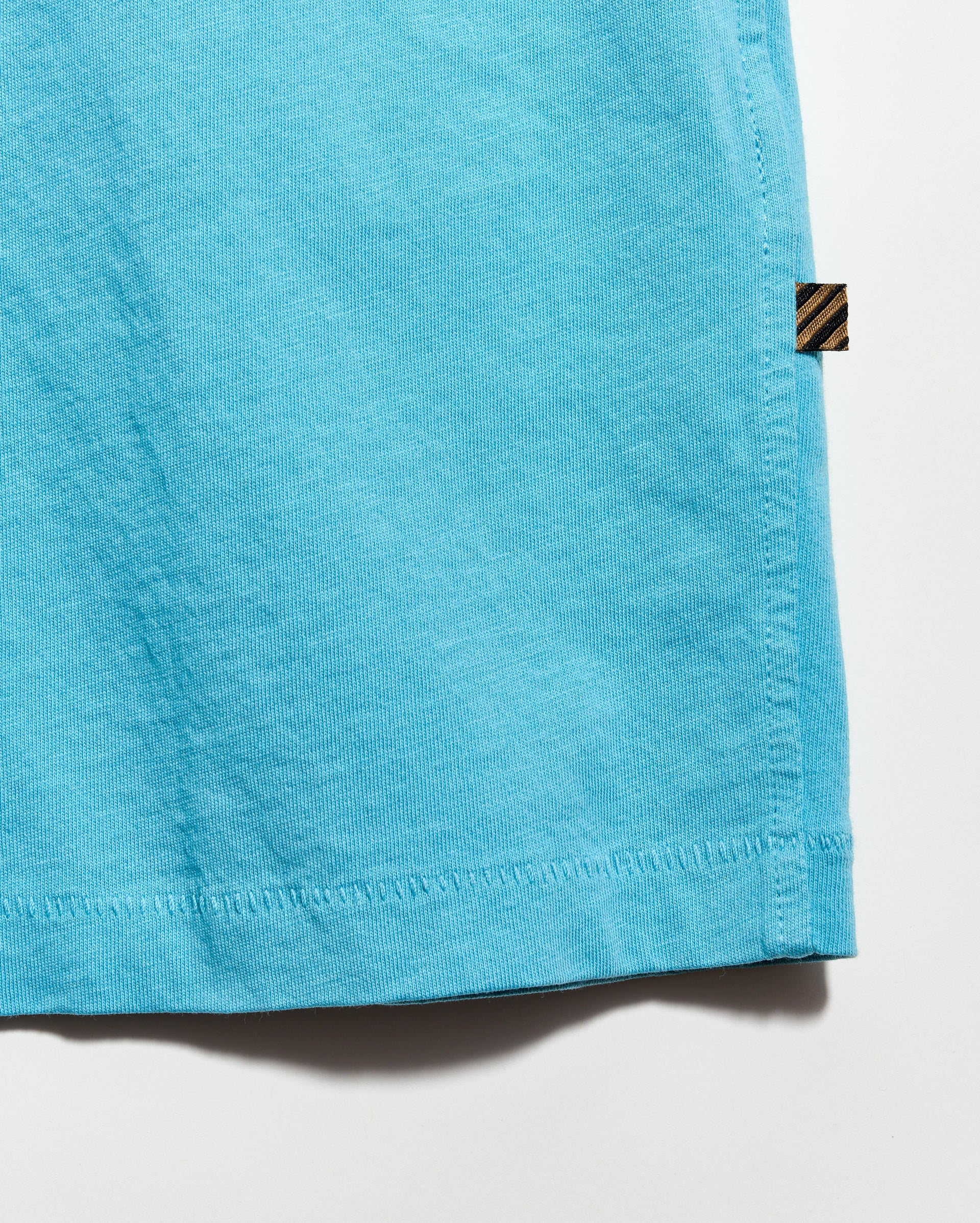 Close-up of a blue fabric edge with a brand label on a white background