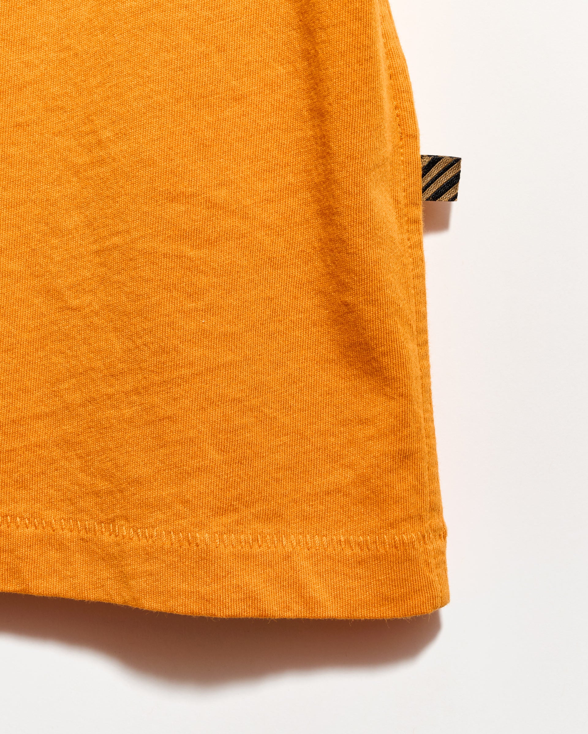 Close-up of an orange garment with a brand tag on a white background