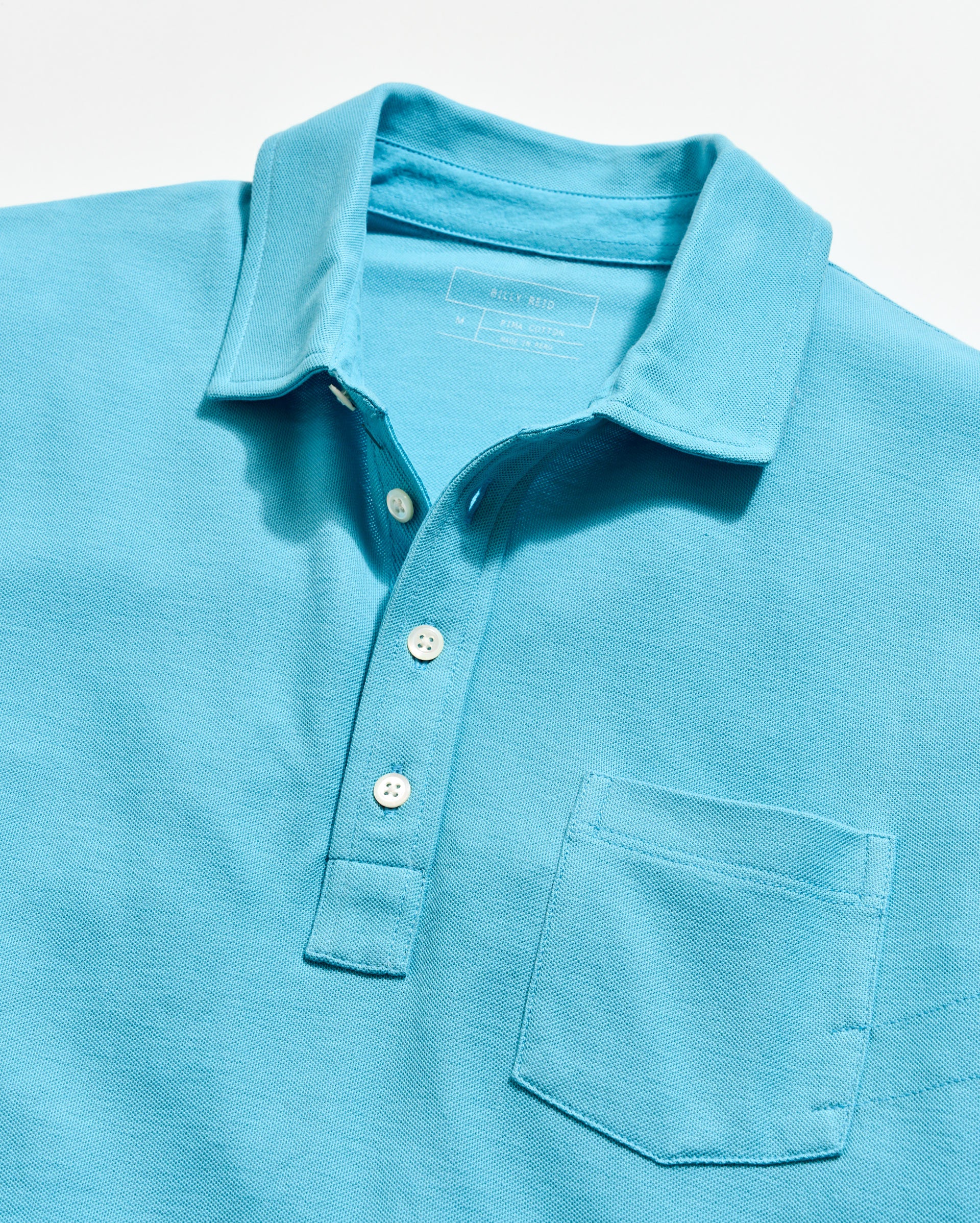 Close-up of a light blue polo shirt with buttons on a white background