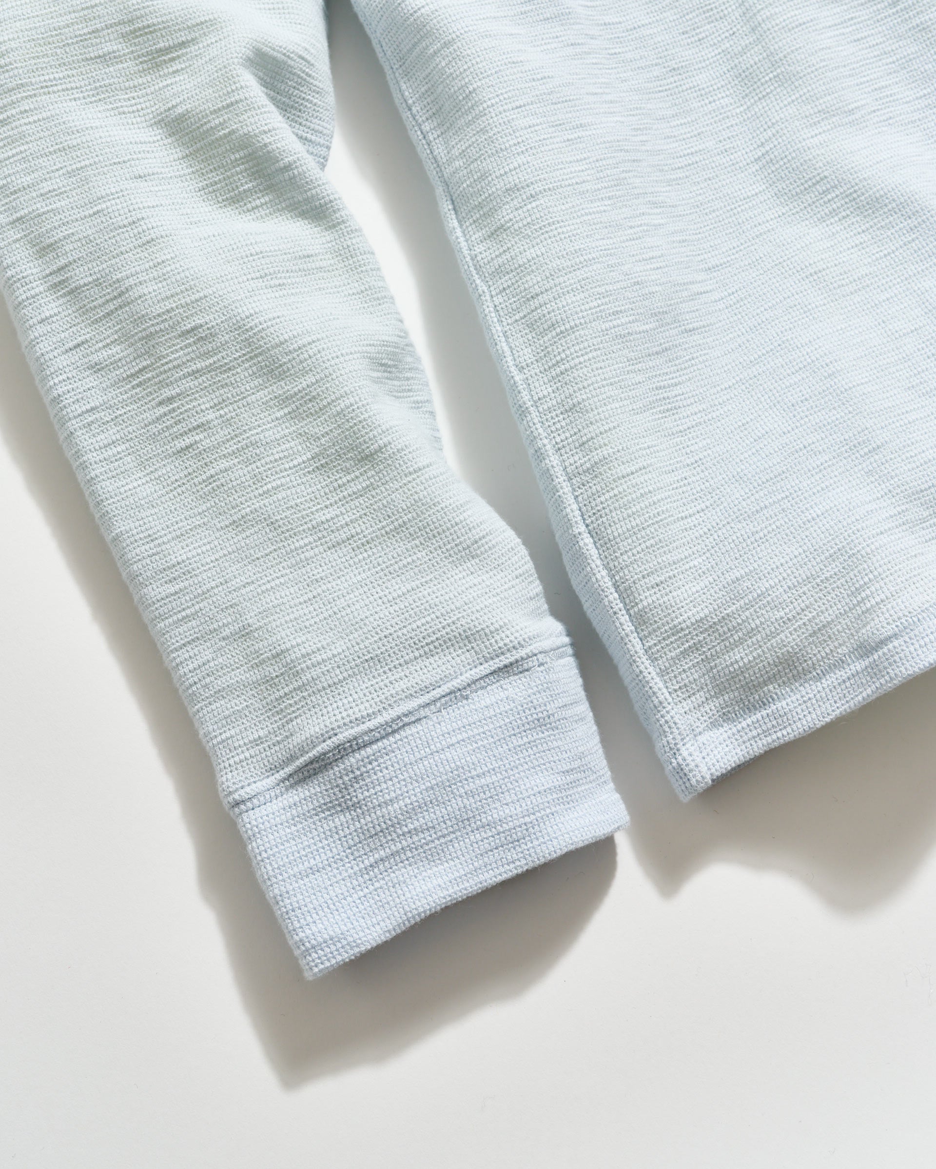 Close-up of light gray fabric with a textured pattern on a white background