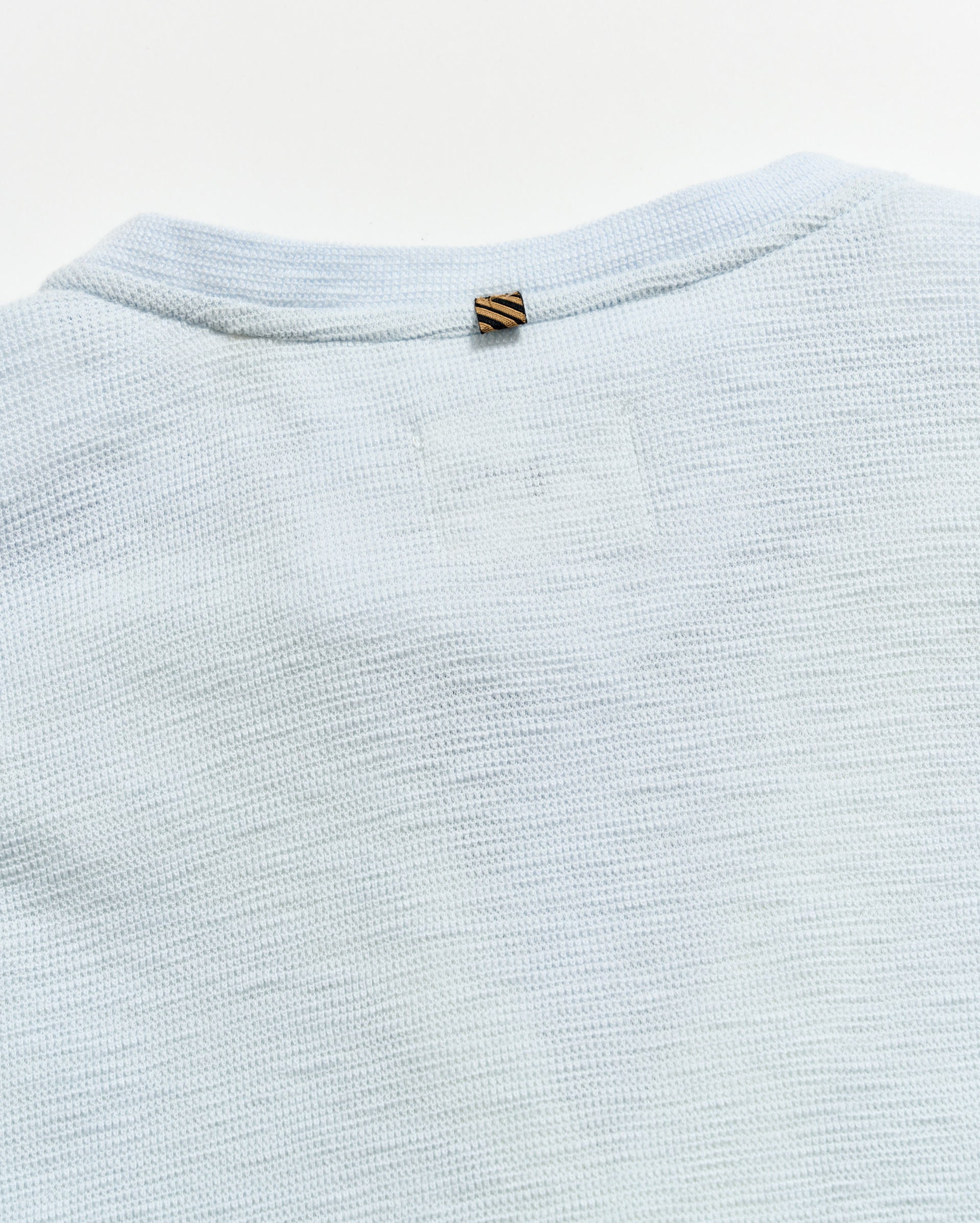 Light blue textured fabric with a brand tag on a white background